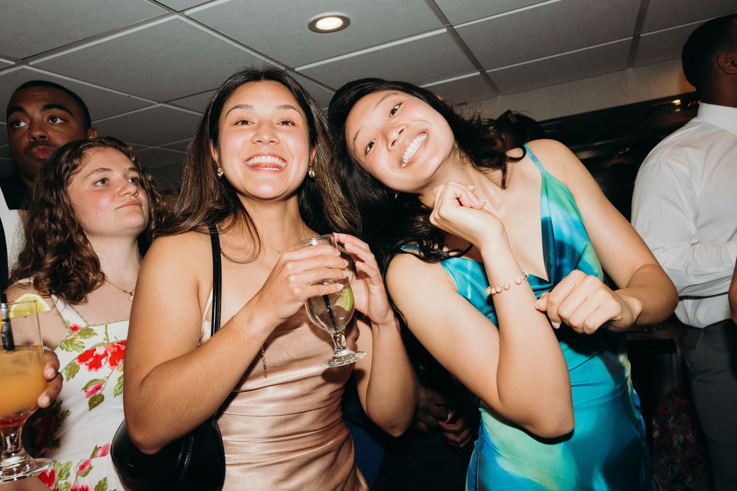 Party guests enjoying drinks and dancing at a festive wedding reception.