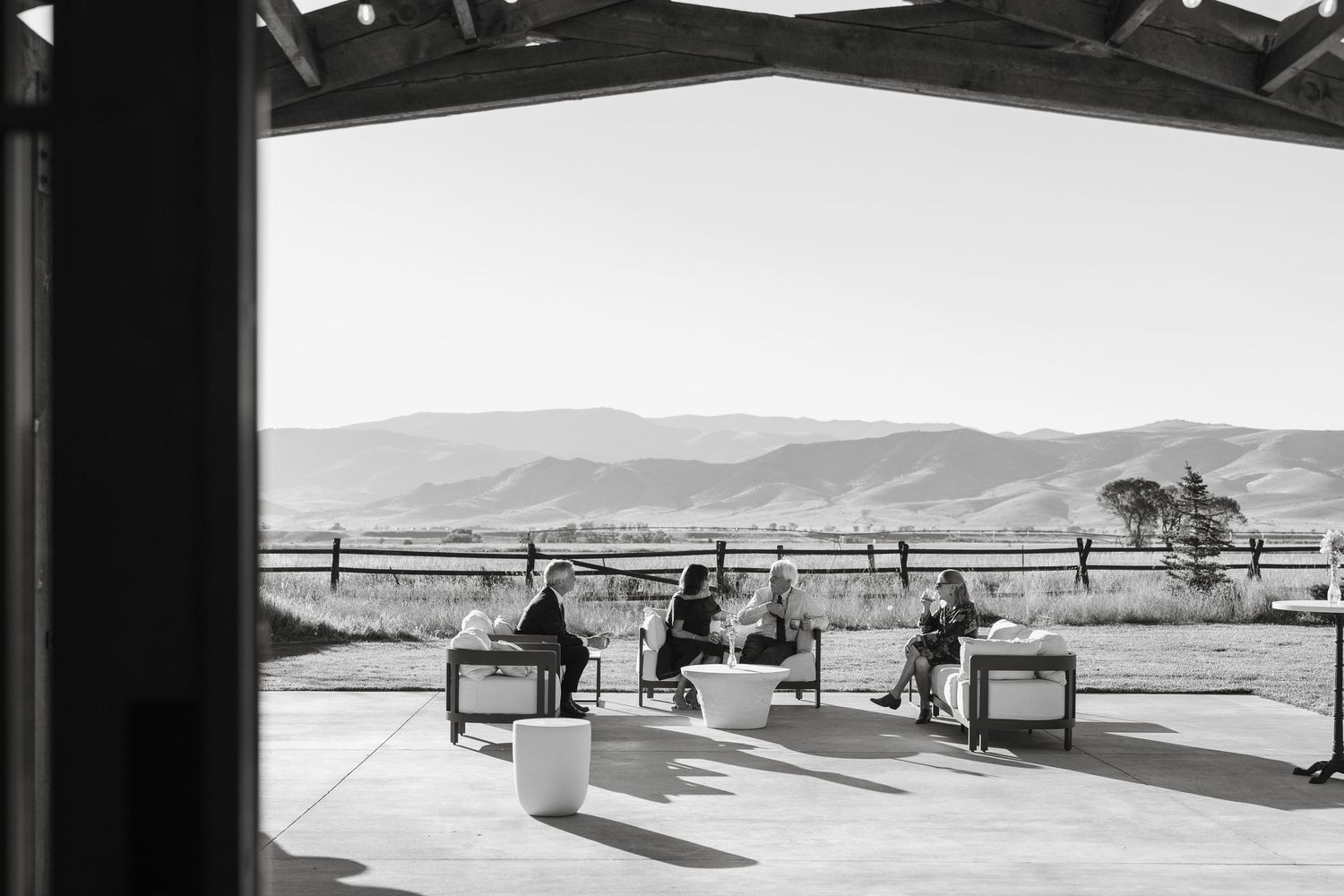 Black and white panoramic landscape view of mountains with horses in the distance.