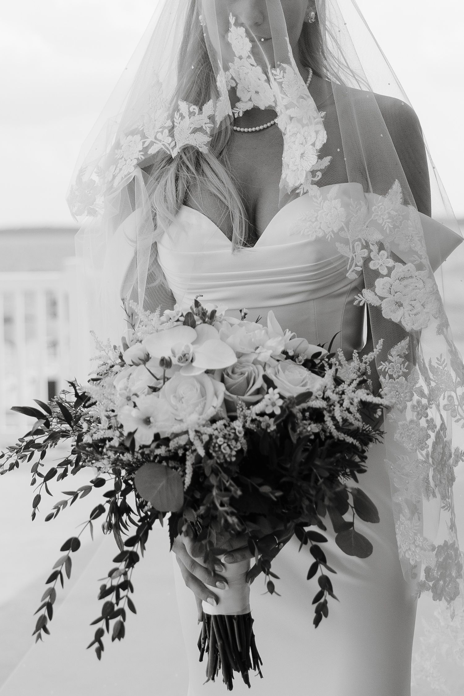 Close-up of a bridal bouquet with white flowers and cascading greenery.