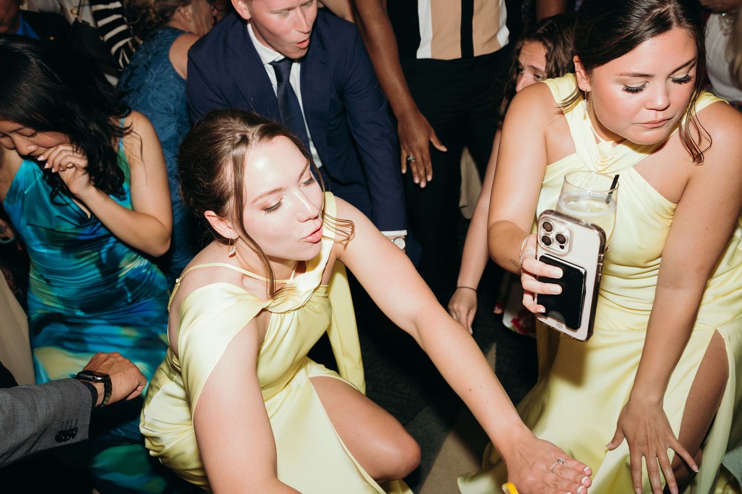 Wedding guests in yellow dresses dancing and enjoying themselves at a reception.