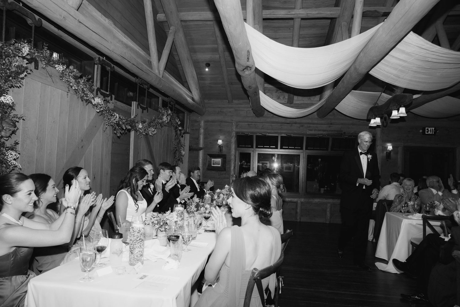 Wedding reception venue with exposed wooden beams and guests celebrating.