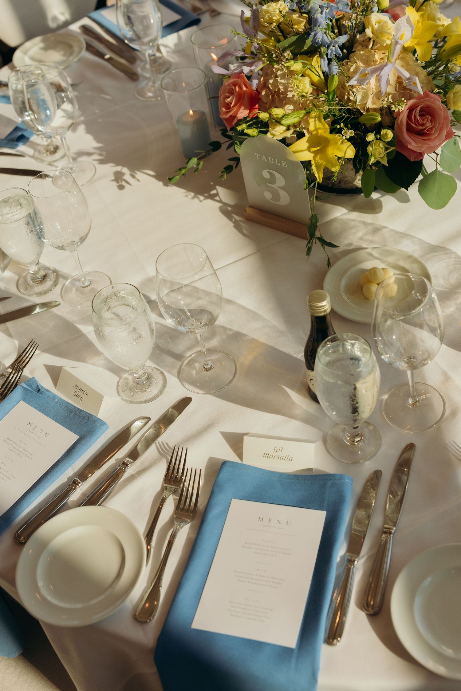 Elegant wedding reception table setting with floral centerpieces and blue accents.