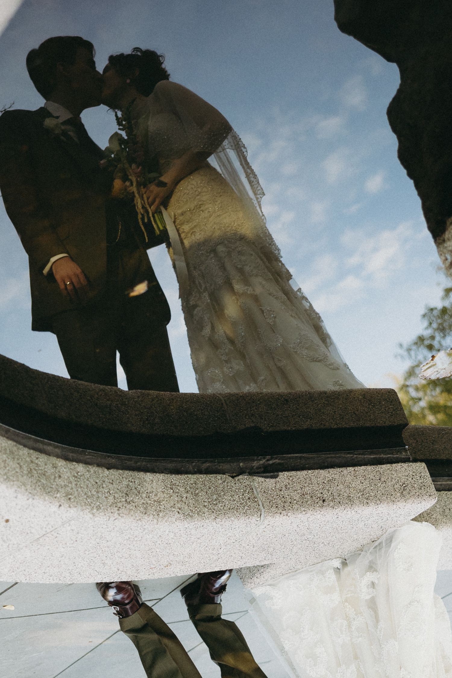 Creative low angle reflection shot of wedding party standing on mirrored surface.