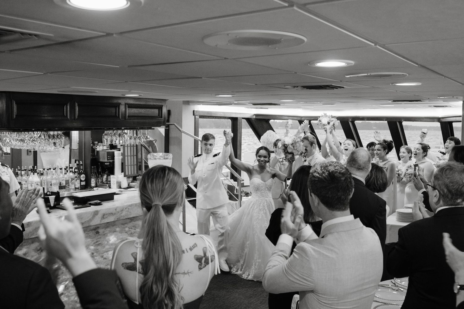 Guests dancing and celebrating in a reception hall with overhead lighting.
