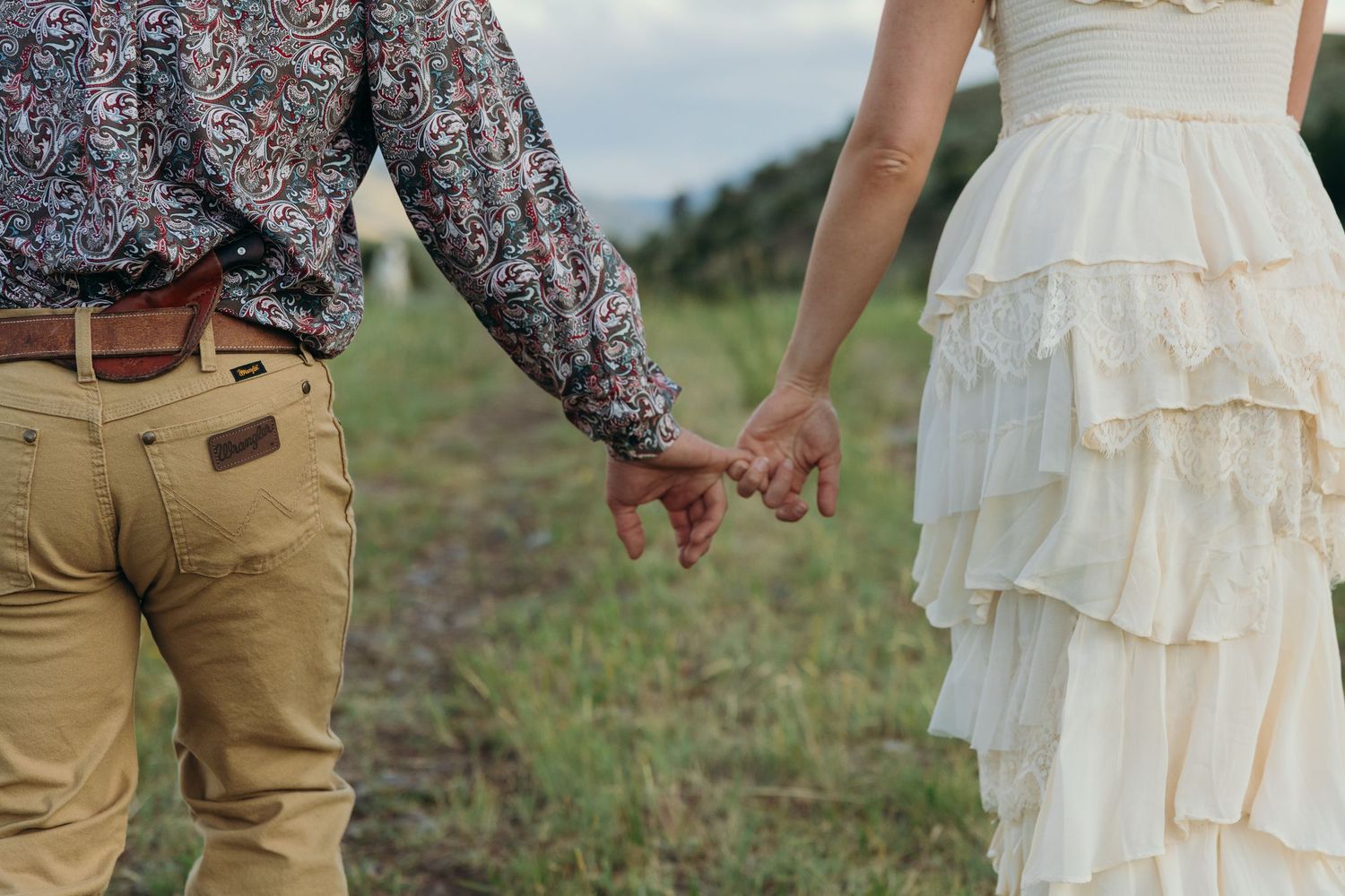 Details of a cream-colored ruffle dress and floral print shirt in an outdoor setting.