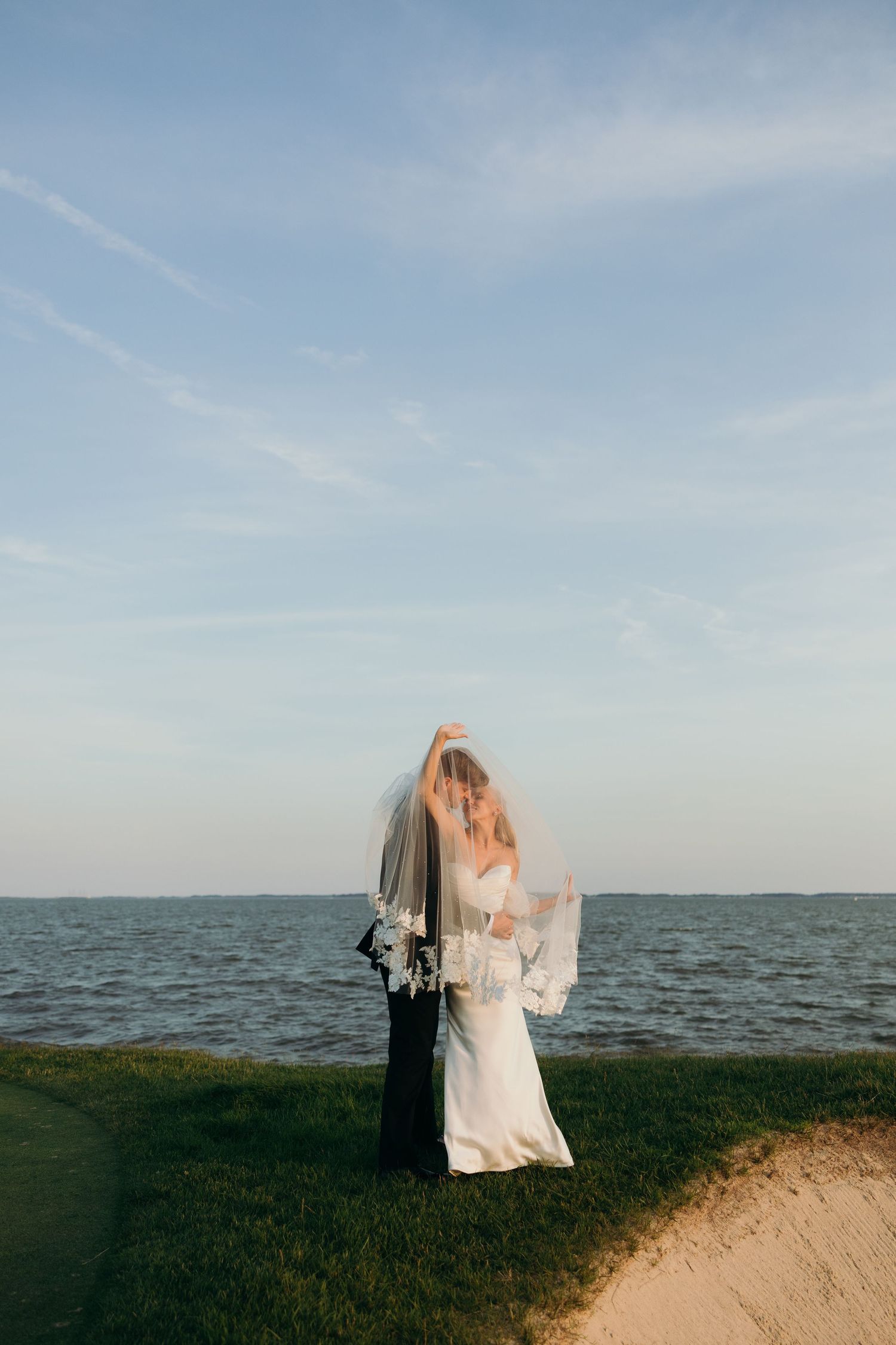 Romantic coastal wedding photos with ocean backdrop at sunset.