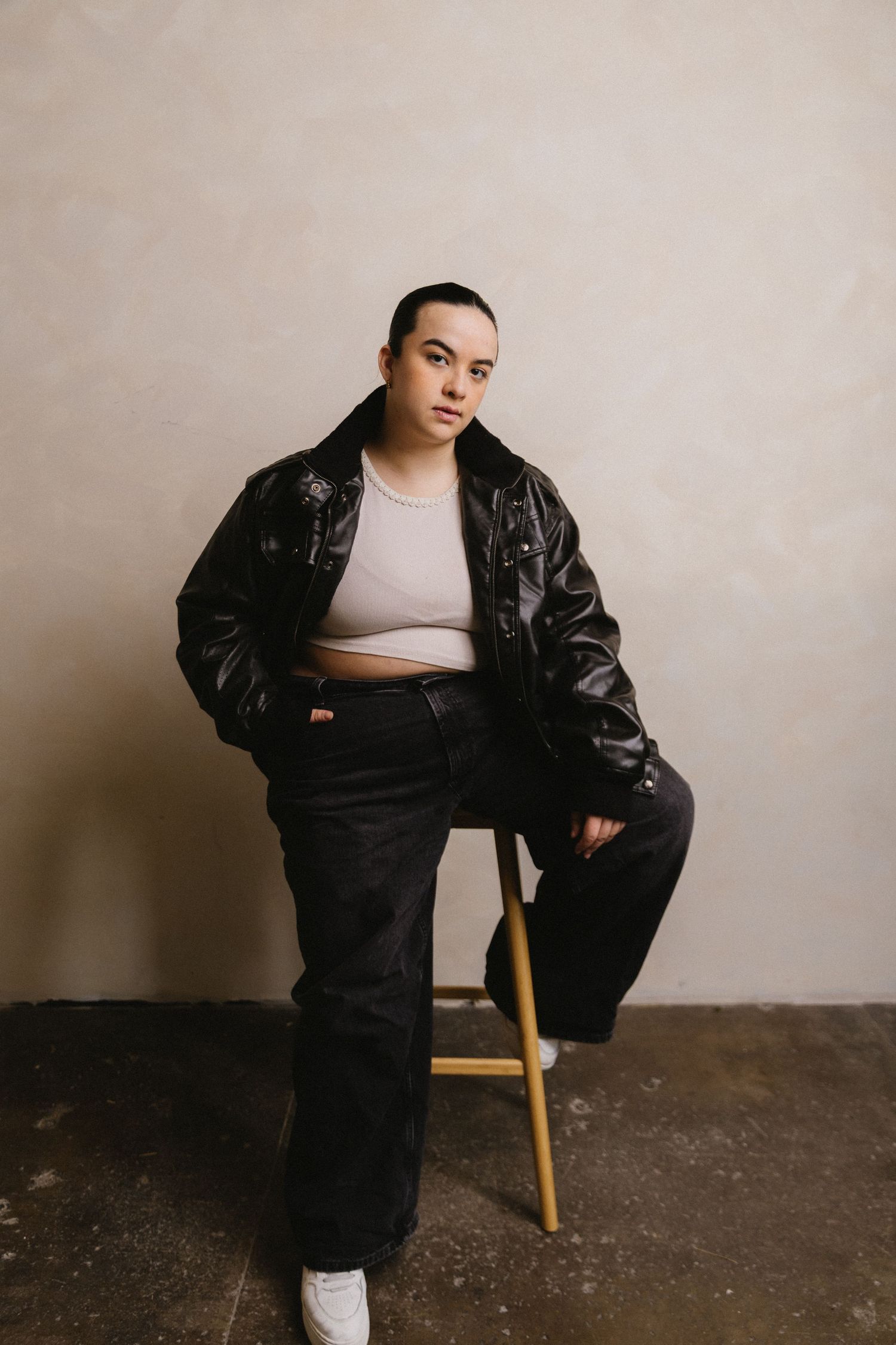 A series of fashion portraits showing someone in a black leather jacket and white top against a minimalist backdrop.