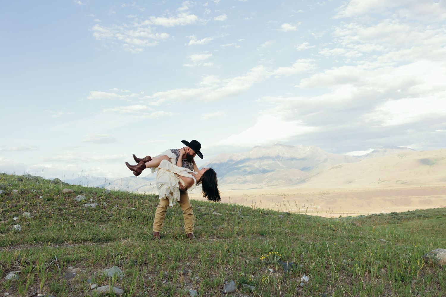 Silhouettes of people doing cartwheels and poses on a grassy hilltop against a cloudy sky.