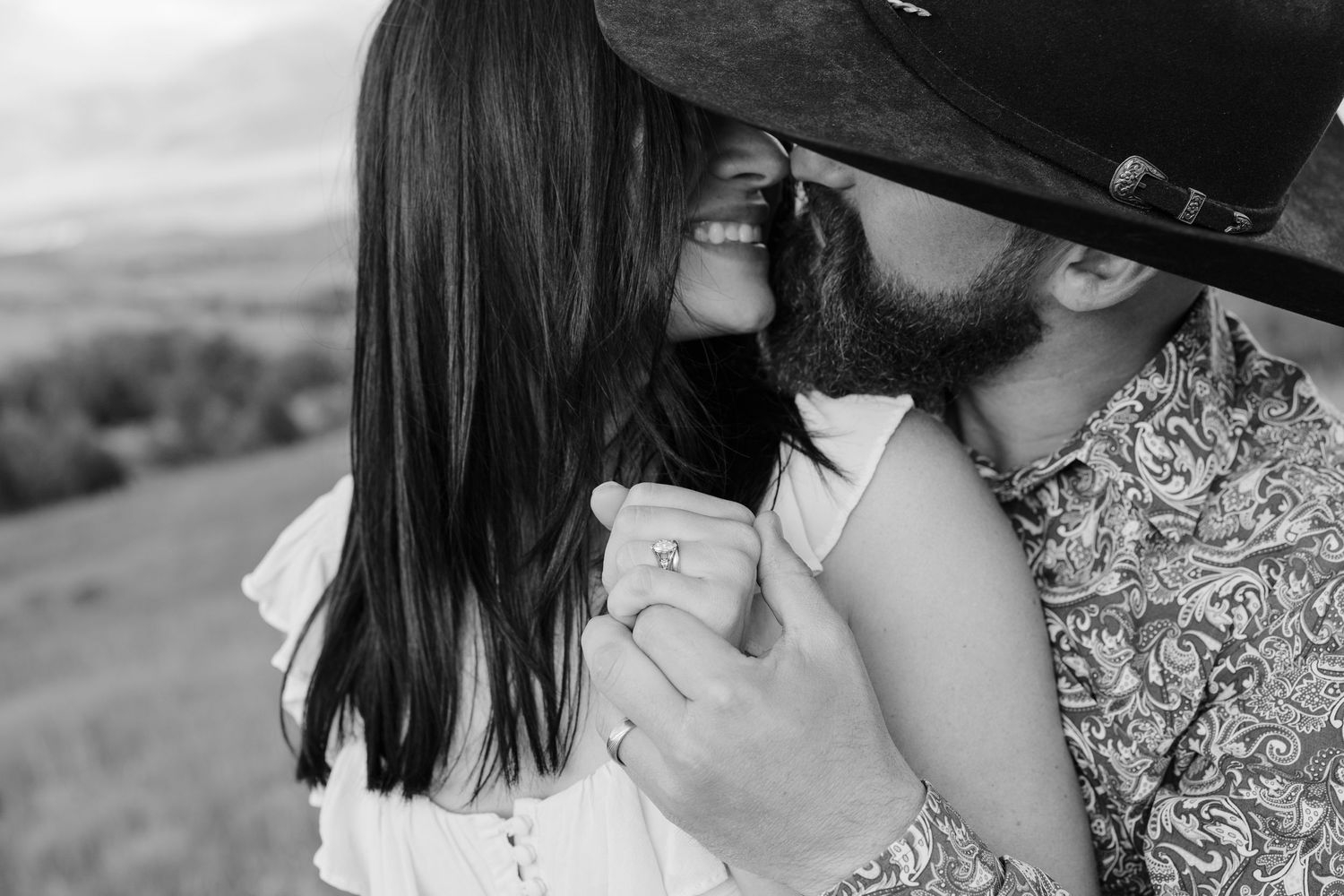 Close-up romantic moment captured in black and white against a natural backdrop.