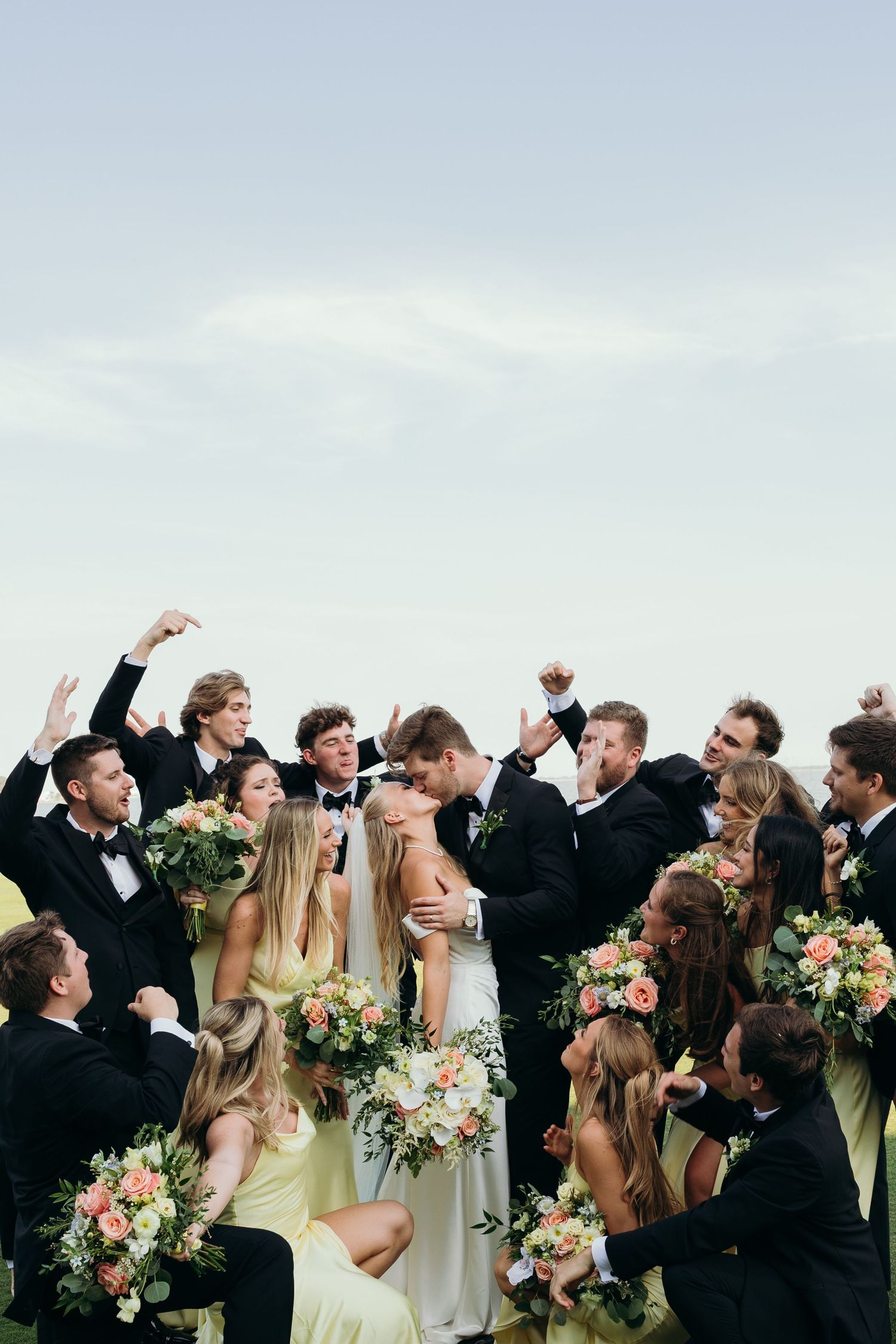 Wedding party in black and yellow attire celebrating joyfully outdoors.