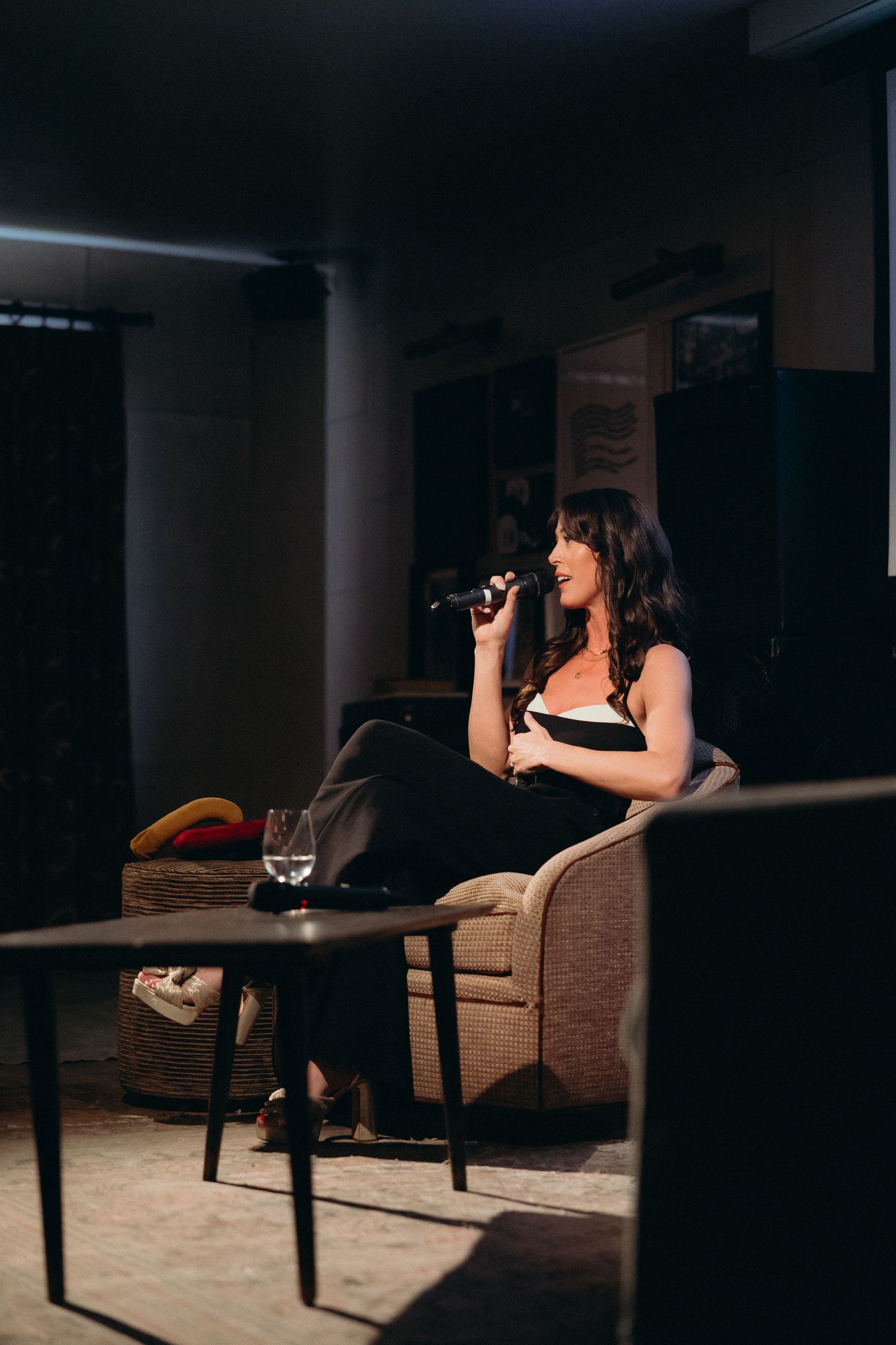 A dimly lit performance space shows Lauren Rogers of Sex Ed For You at SOHO House NYC