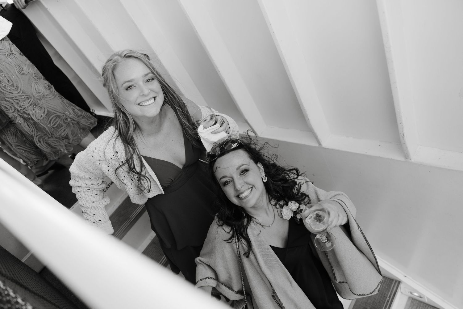 Wedding party members pose and celebrate on a white architectural backdrop.