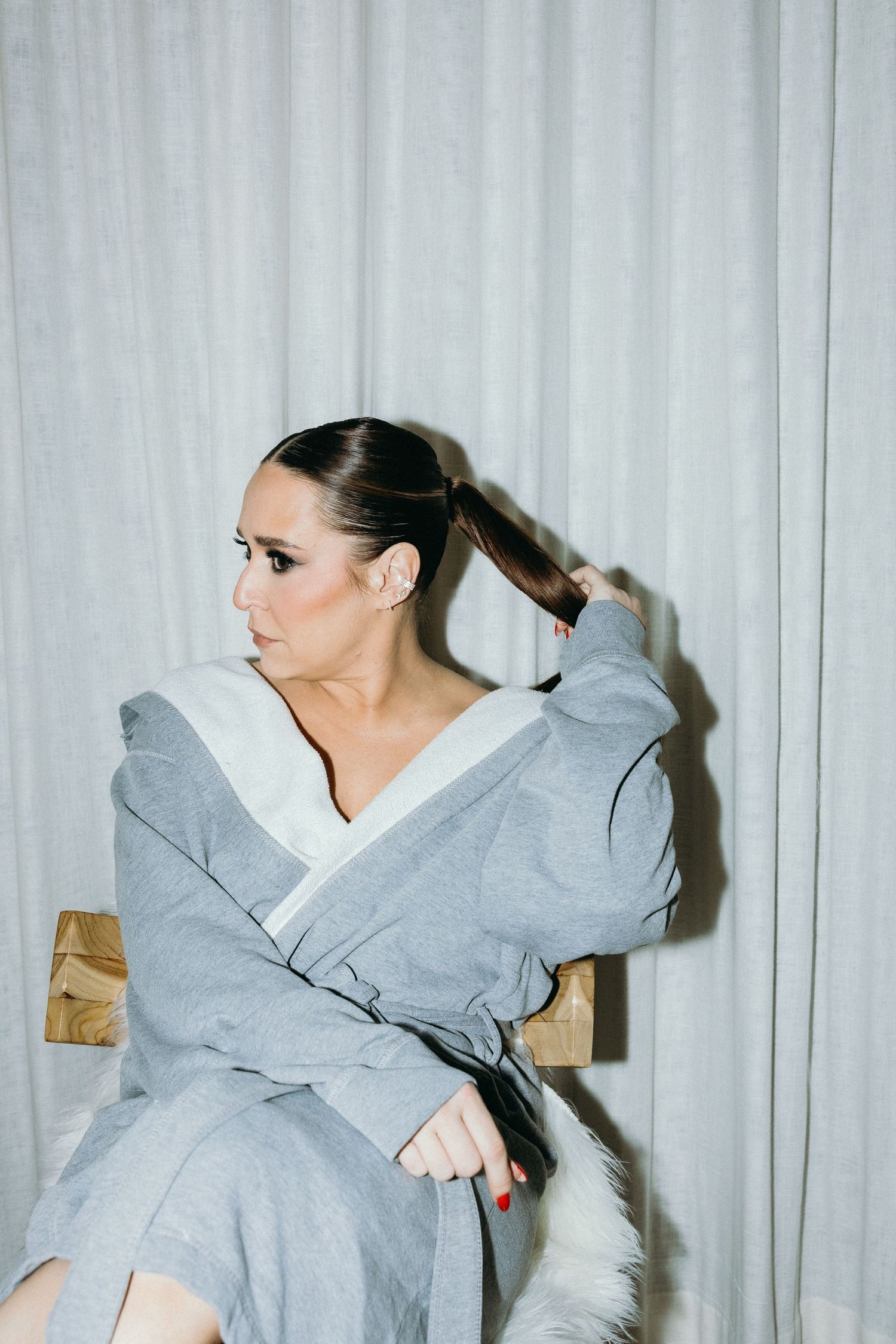 Fashion model poses in an oversized gray hoodie against a white backdrop in a dynamic photo series.