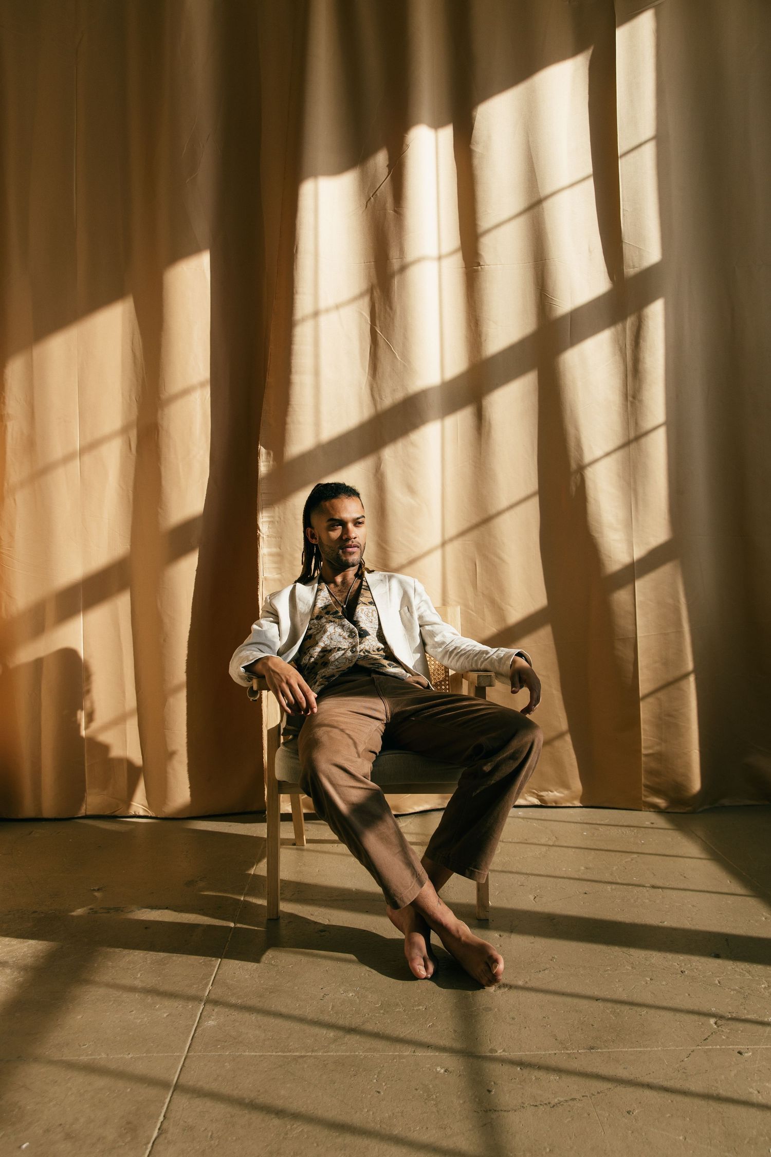 Brandon Cameron Actor sits on the floor in dramatic lighting with strong window shadows casting geometric patterns on the wall.