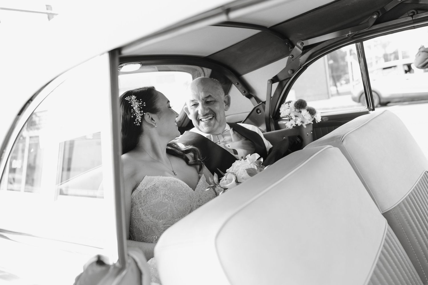 A black and white photo showing people sitting inside a classic Volkswagen Beetle car interior.