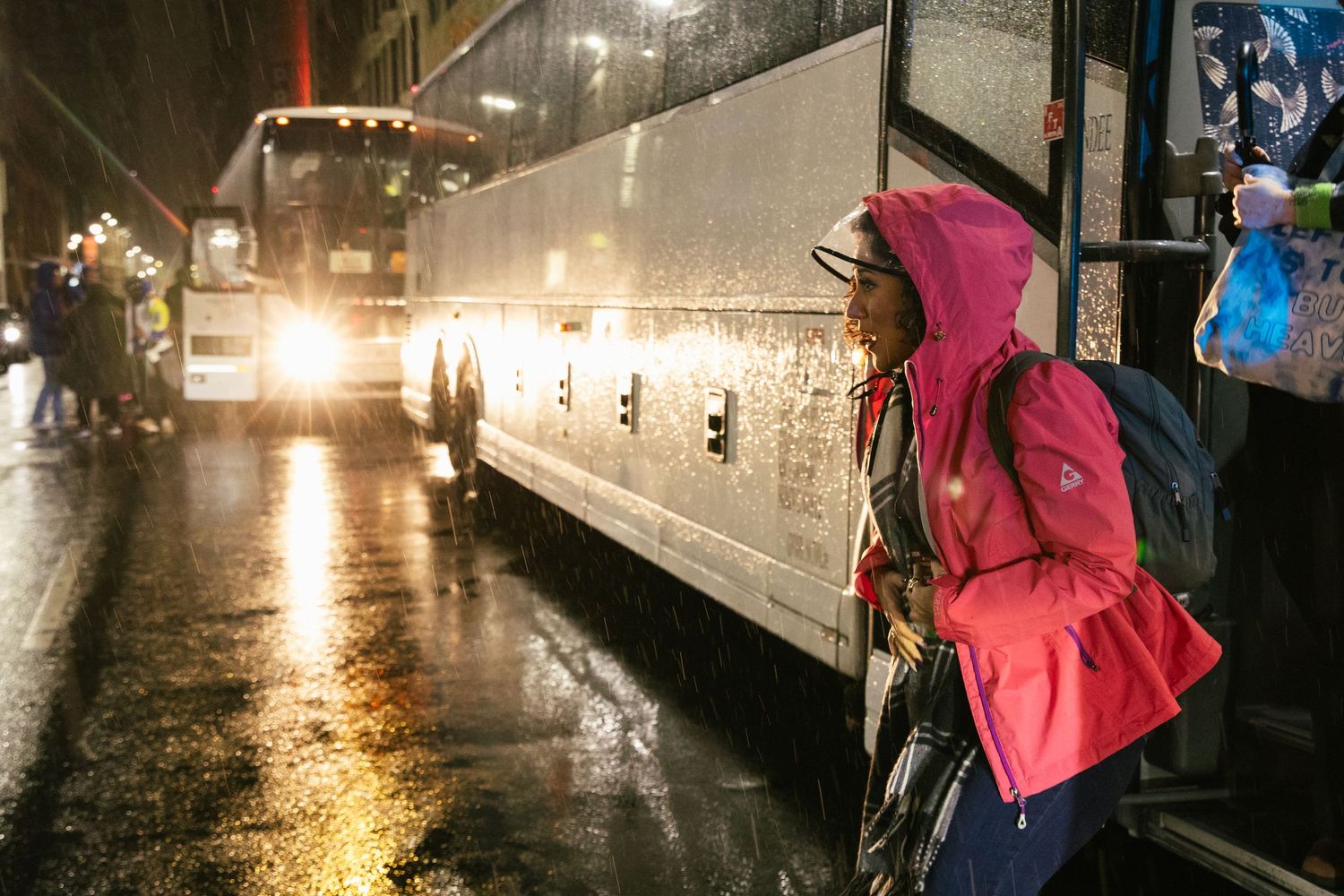 Rainy night street scene with reflective wet pavement and glowing lights.