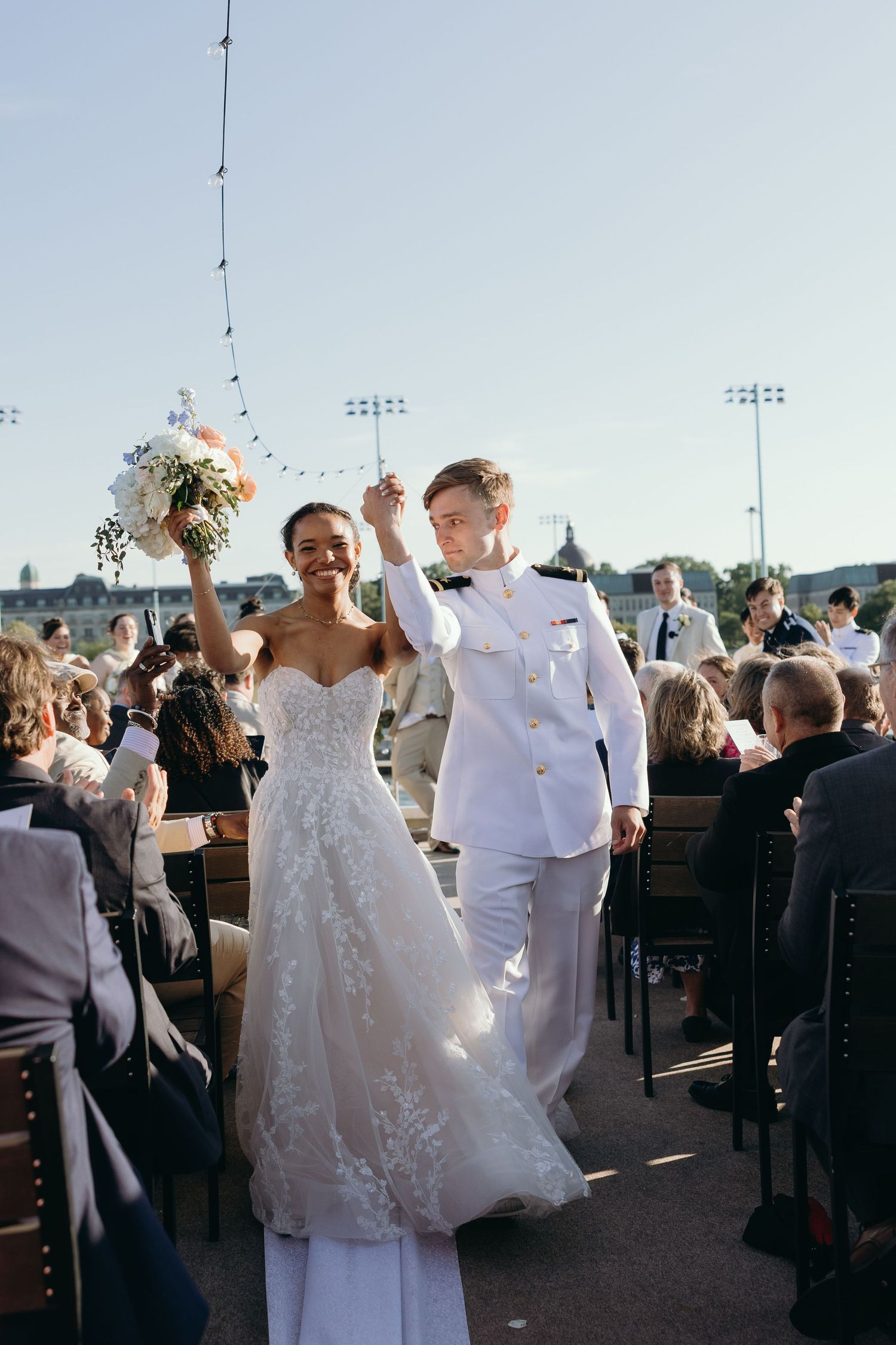 Wedding party members dance and celebrate during an outdoor reception.