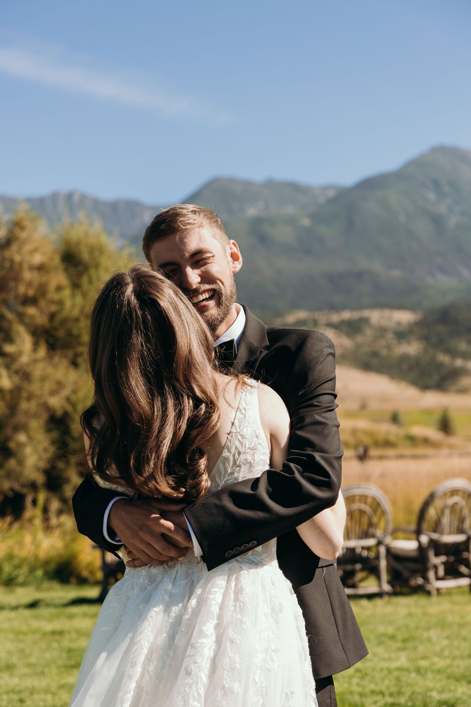 A joyful couple embraces during their outdoor mountain wedding ceremony.