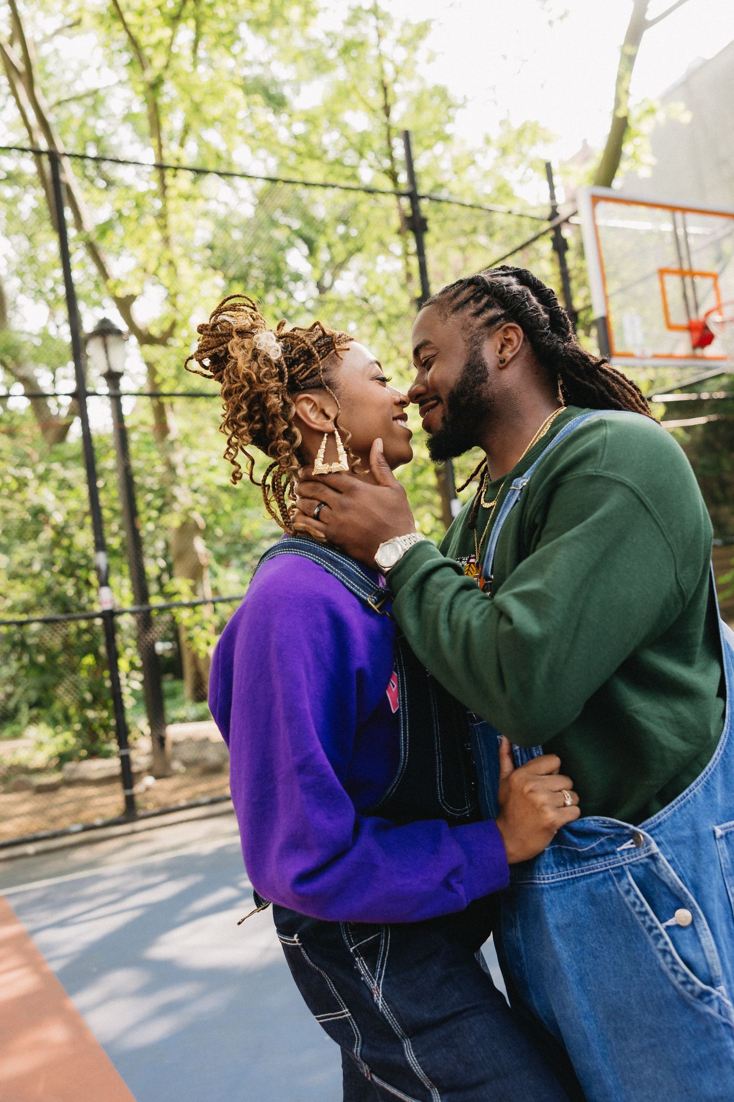 A couple shares a playful moment together on a basketball court in casual attire.