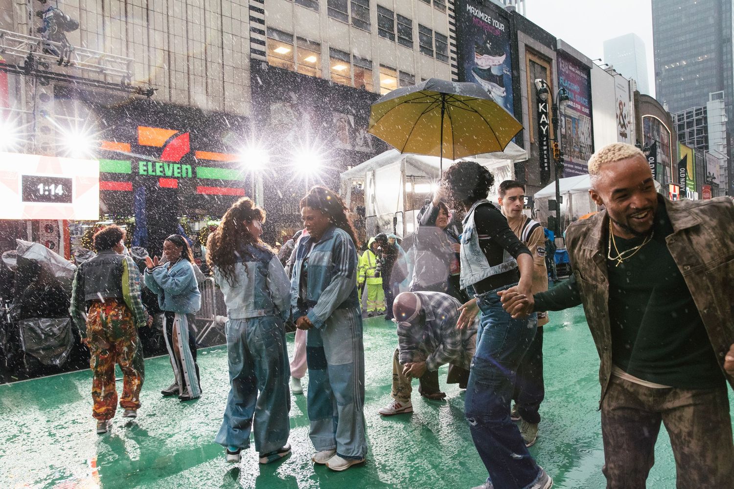 A festive street party with people dancing in the rain on a green surface.