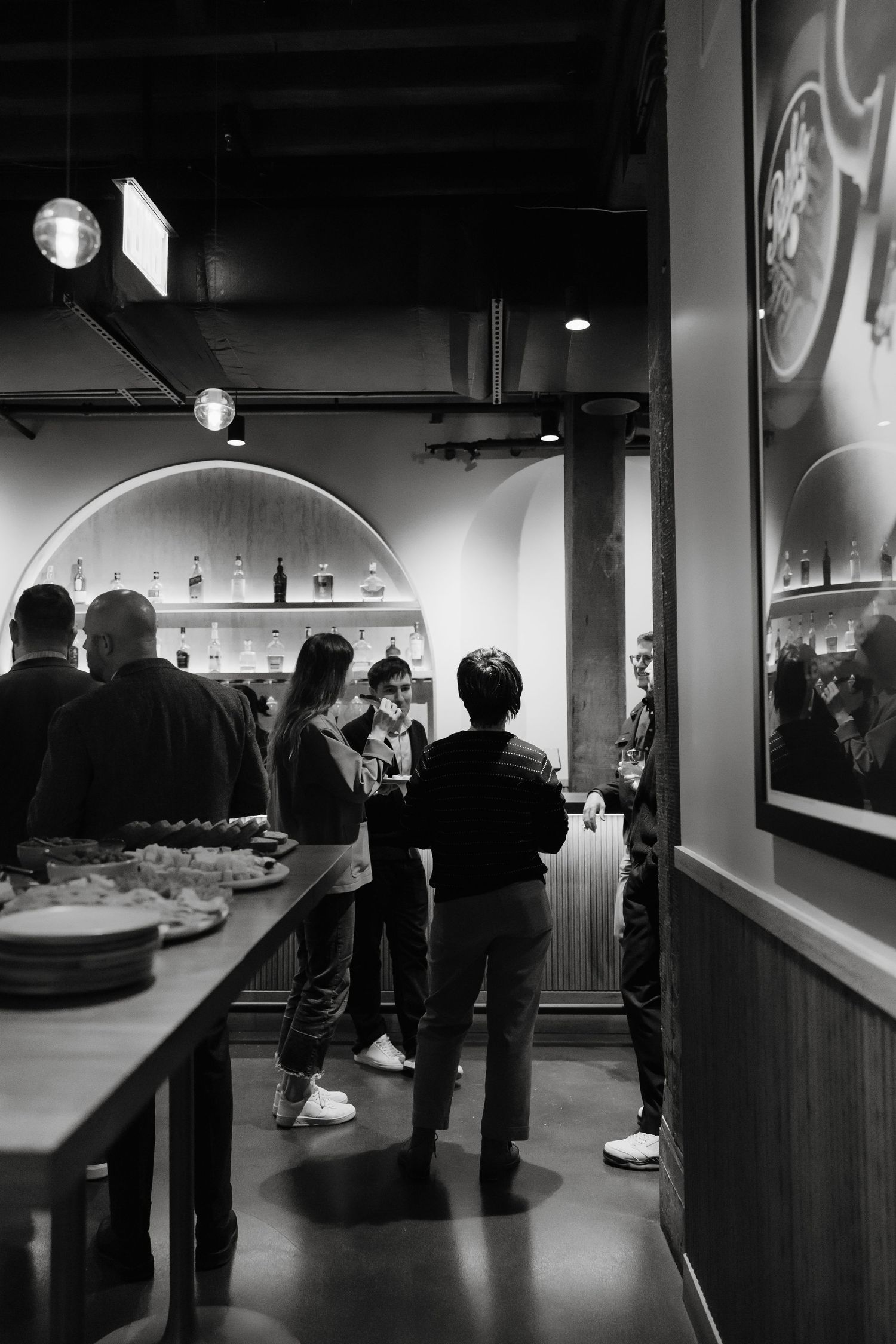 Silhouettes of people viewing exhibits in a dimly lit museum gallery space.