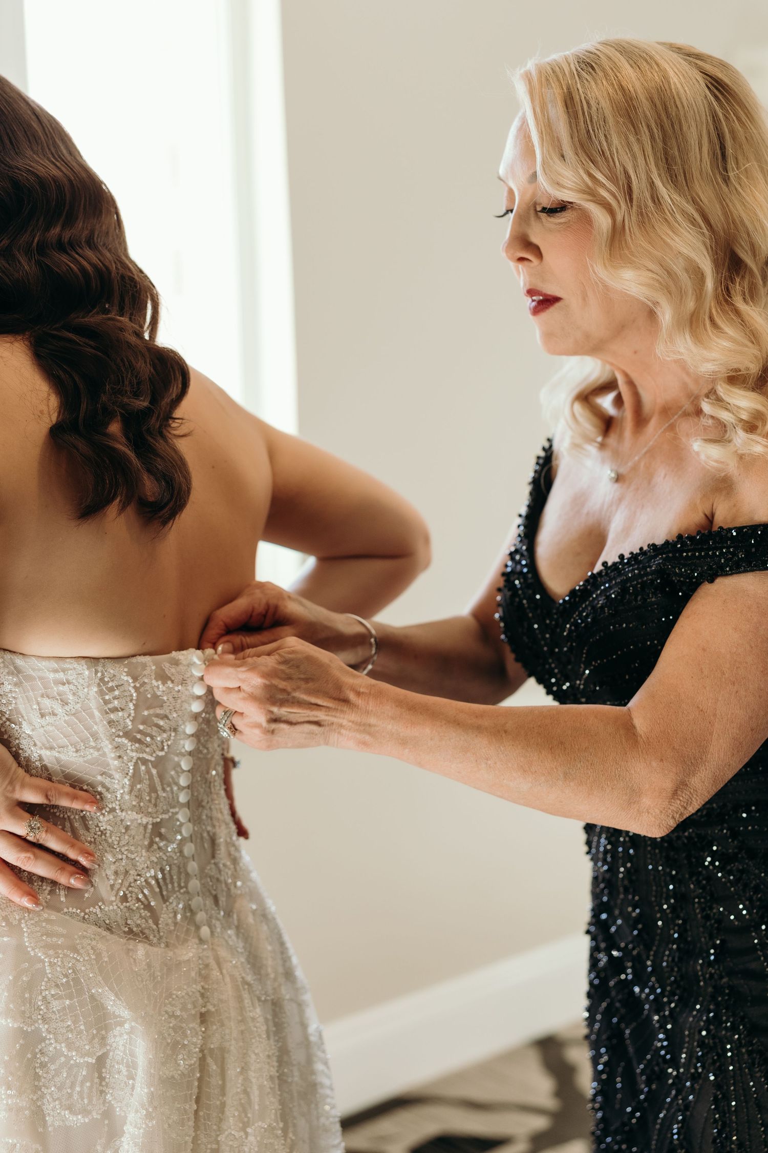 Close up of hands adjusting white lace wedding dress details while getting ready.