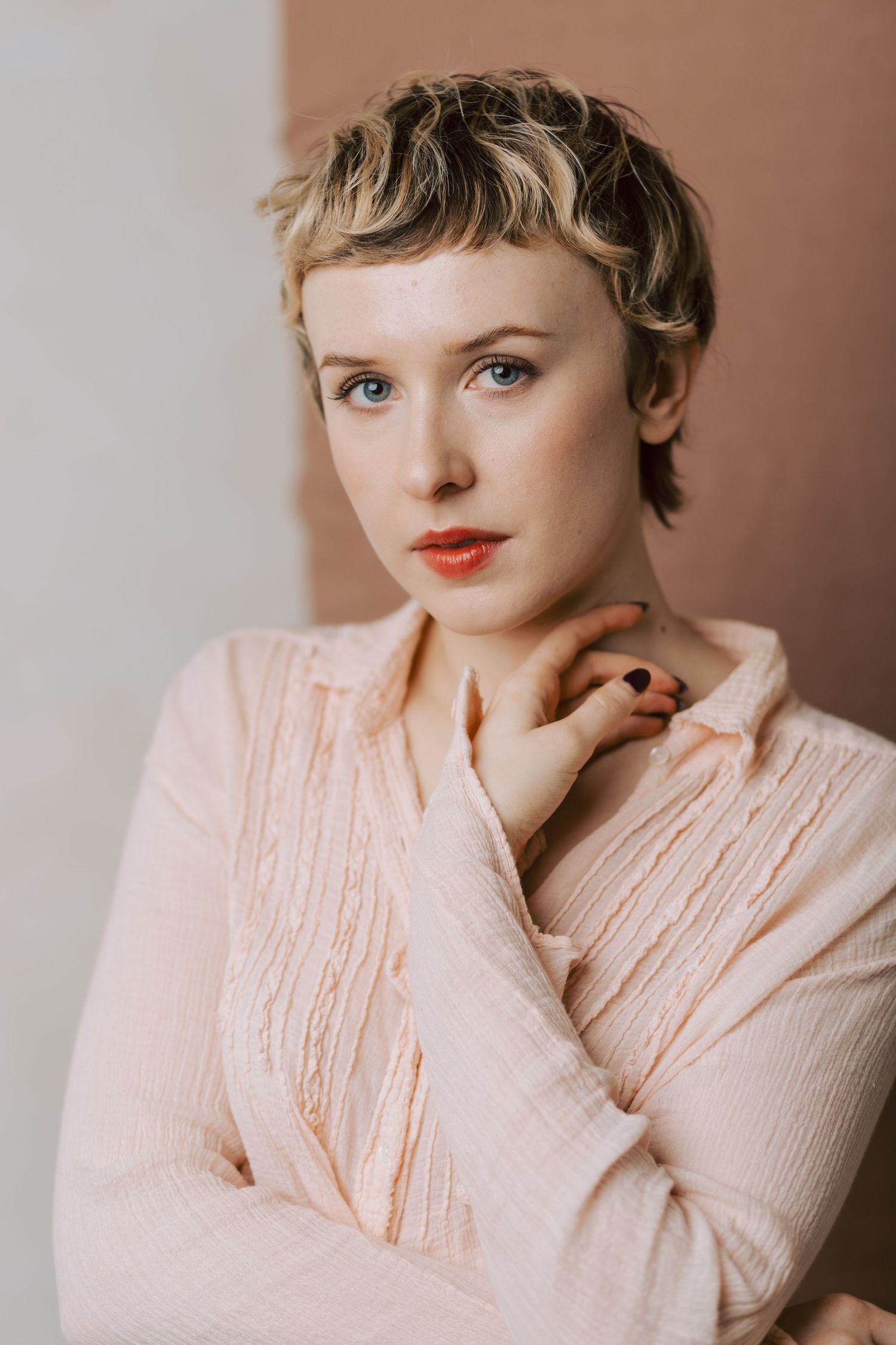 A series of soft, feminine portraits featuring a short-haired figure in a pale pink ruffled blouse against a neutral backdrop.
