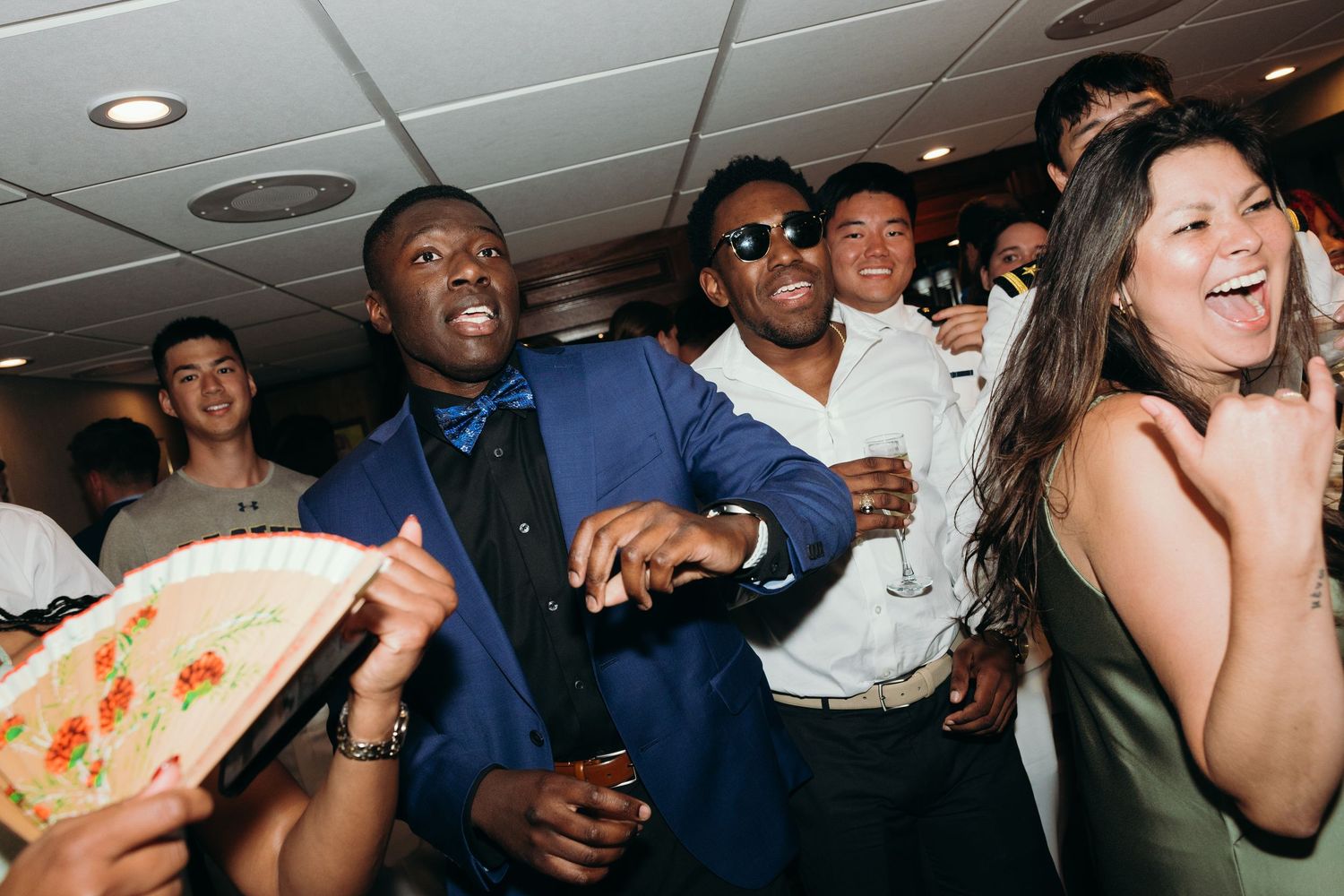 Guests dancing and laughing at a lively wedding reception with colorful formal attire.