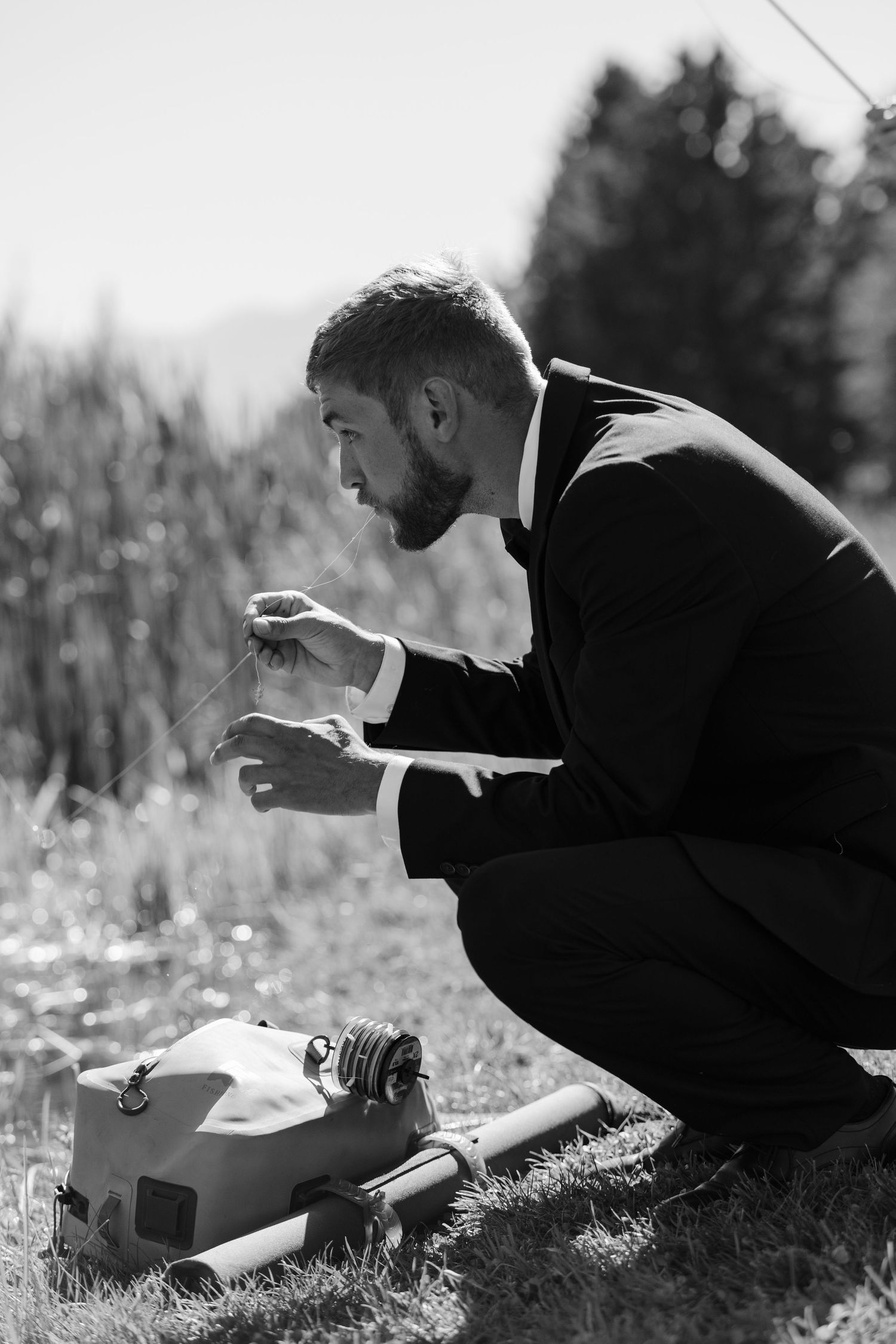 A silhouette of someone examining small objects in a field during golden hour.