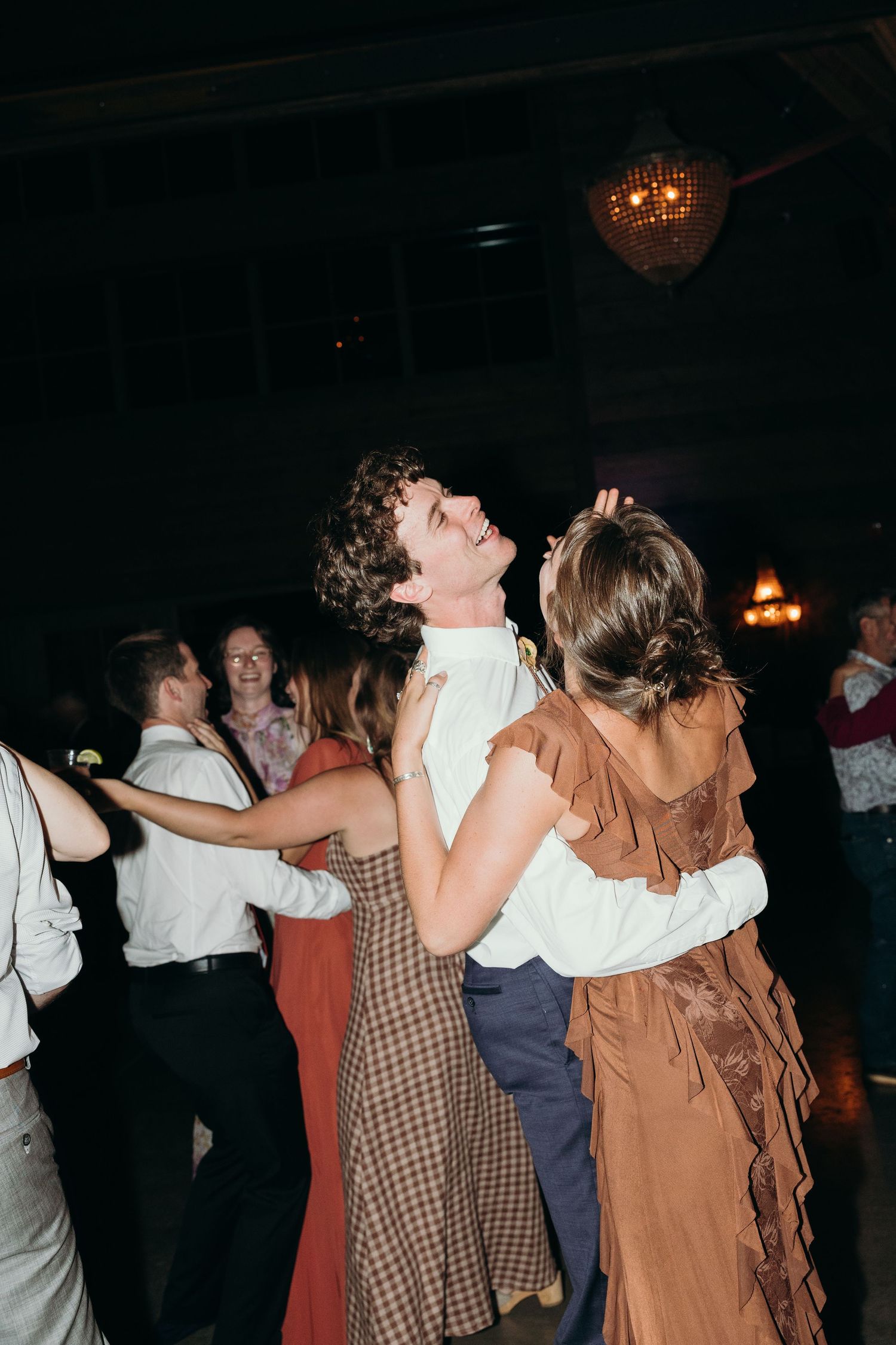 Wedding guests dancing together in formal attire at an evening reception.