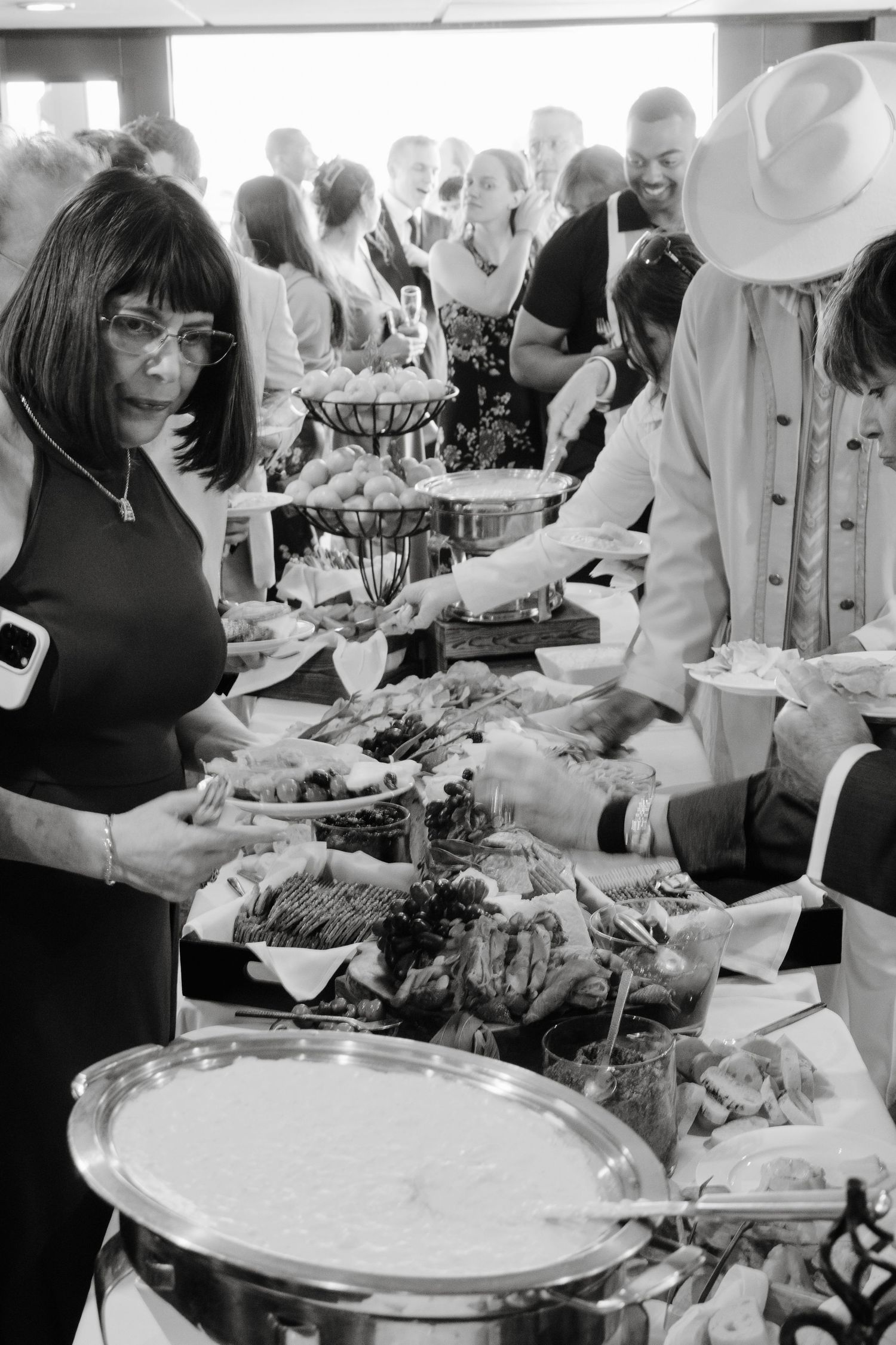 Wedding guests serve themselves at an elegant buffet line with multiple food stations.