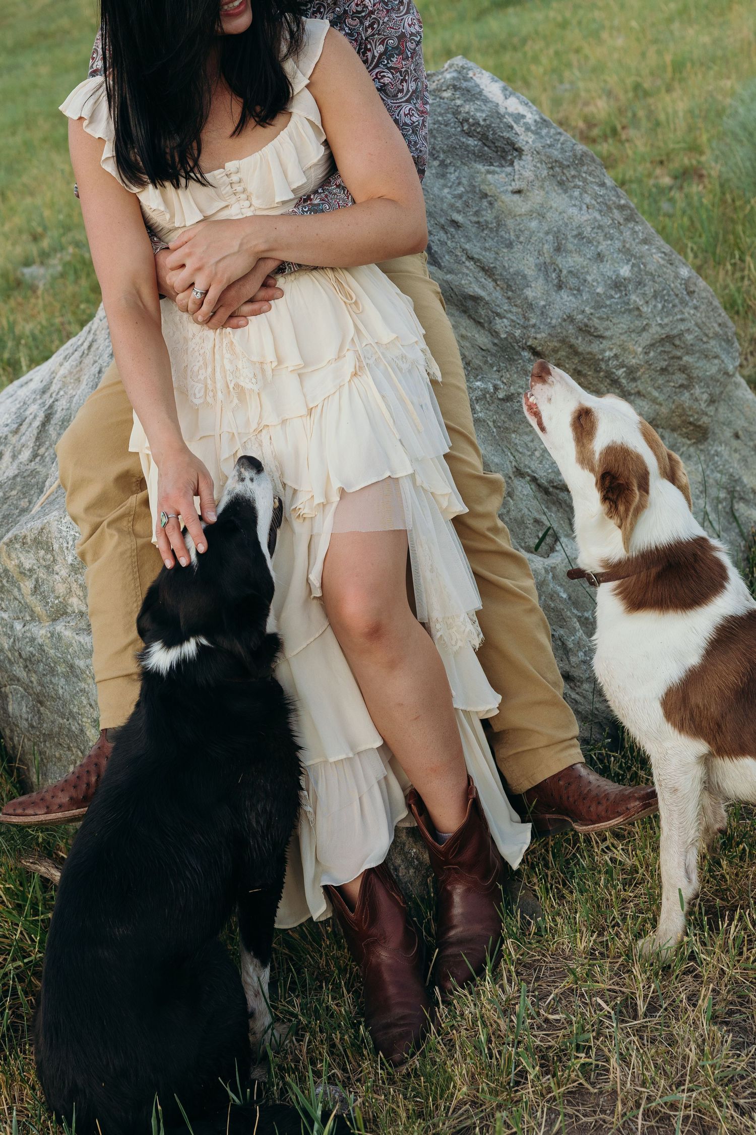 Couple sitting on rocks with their dogs during an outdoor engagement photoshoot.