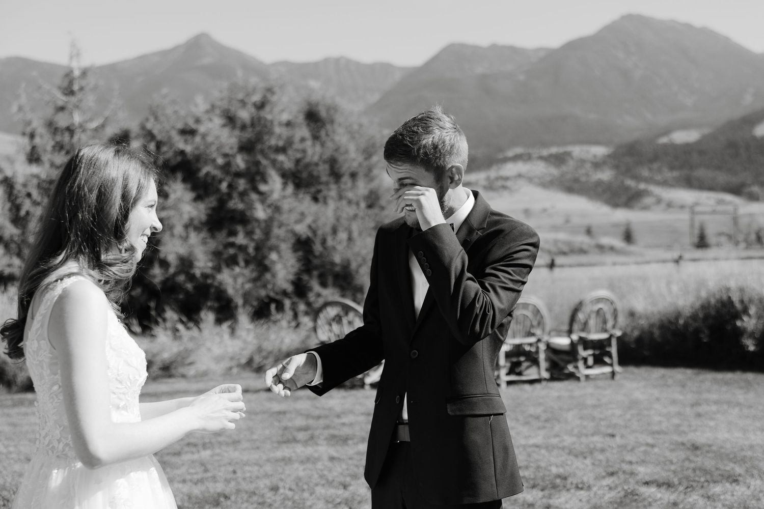 A wedding couple shares their first dance outdoors with mountain peaks in the background.