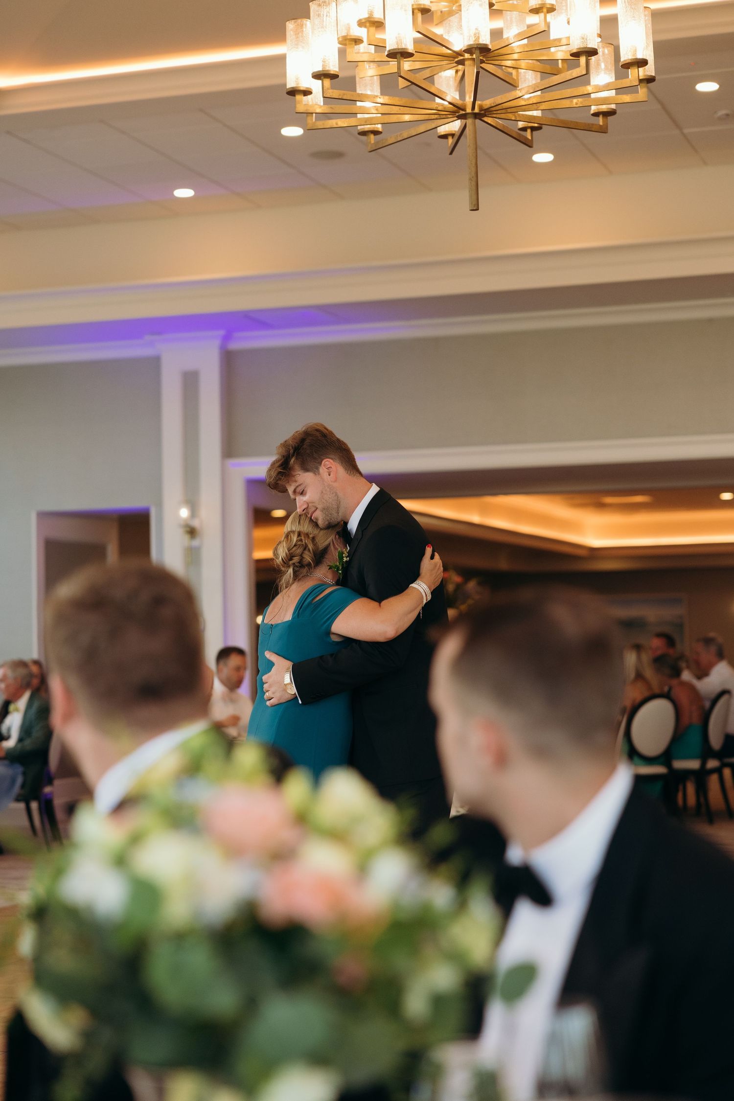 Wedding reception dance floor with guests celebrating under warm lighting and chandeliers.