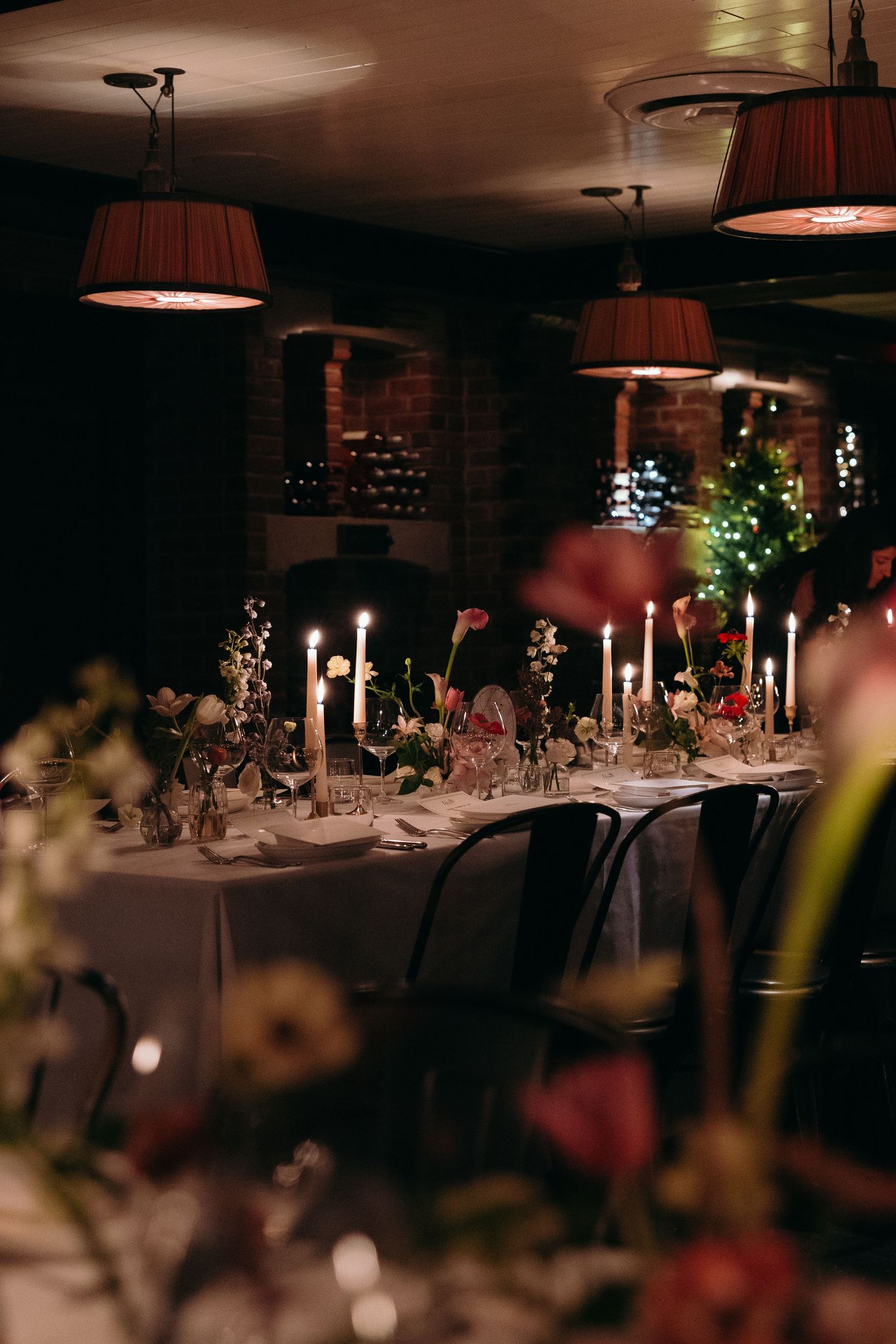 Elegant table settings with glowing candles and string lights create a romantic ambiance at an evening reception at a luxury wedding.