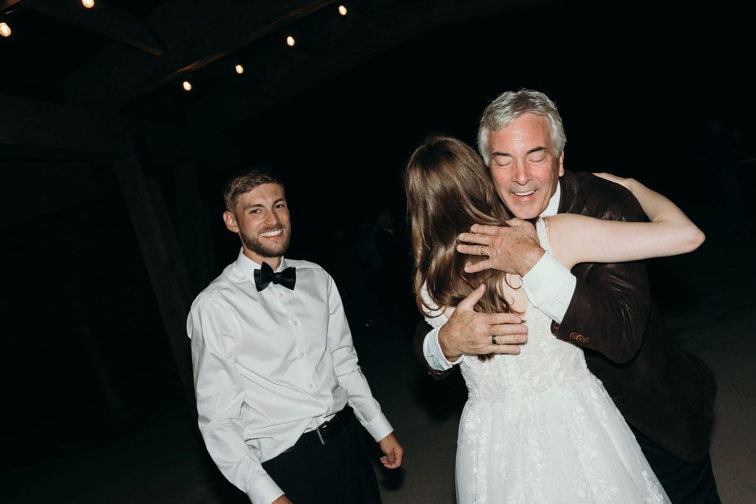 Couples dancing and celebrating at a dimly lit reception party.