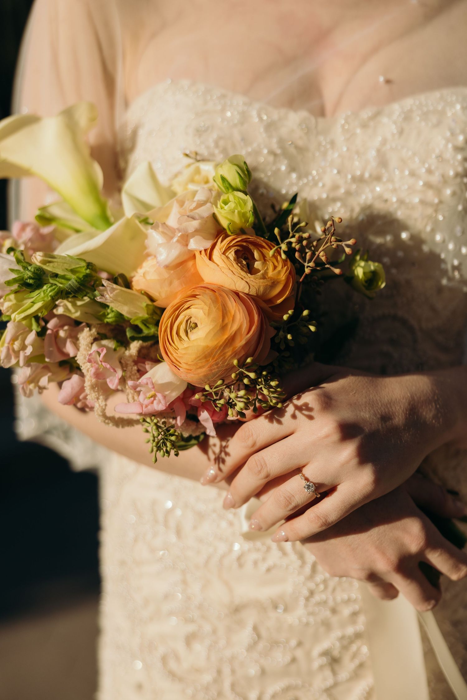 Close-up of delicate floral wrist corsage with peach ranunculus and greenery.
