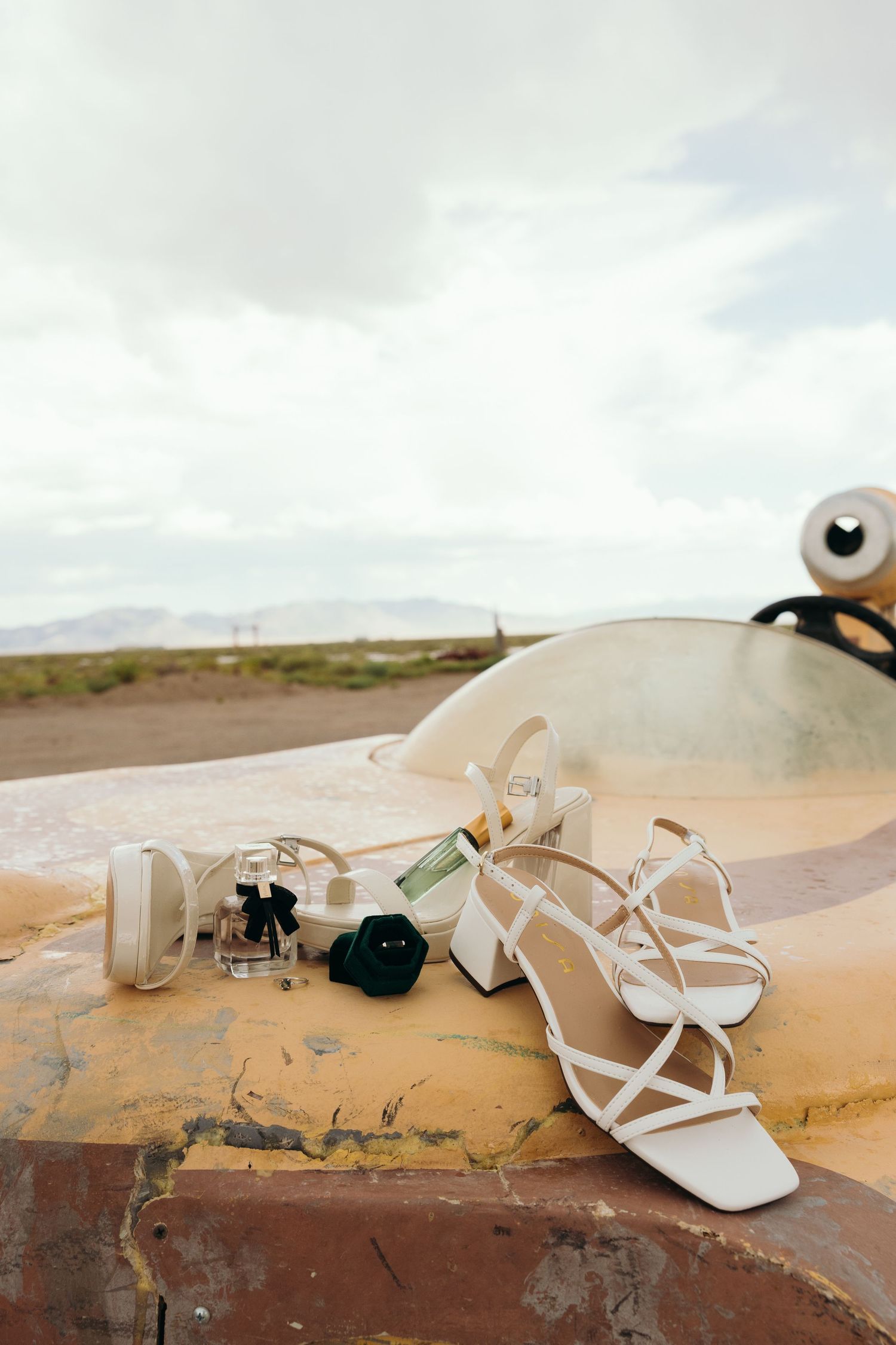 White bridal sandals arranged on rustic surface with desert landscape in background.