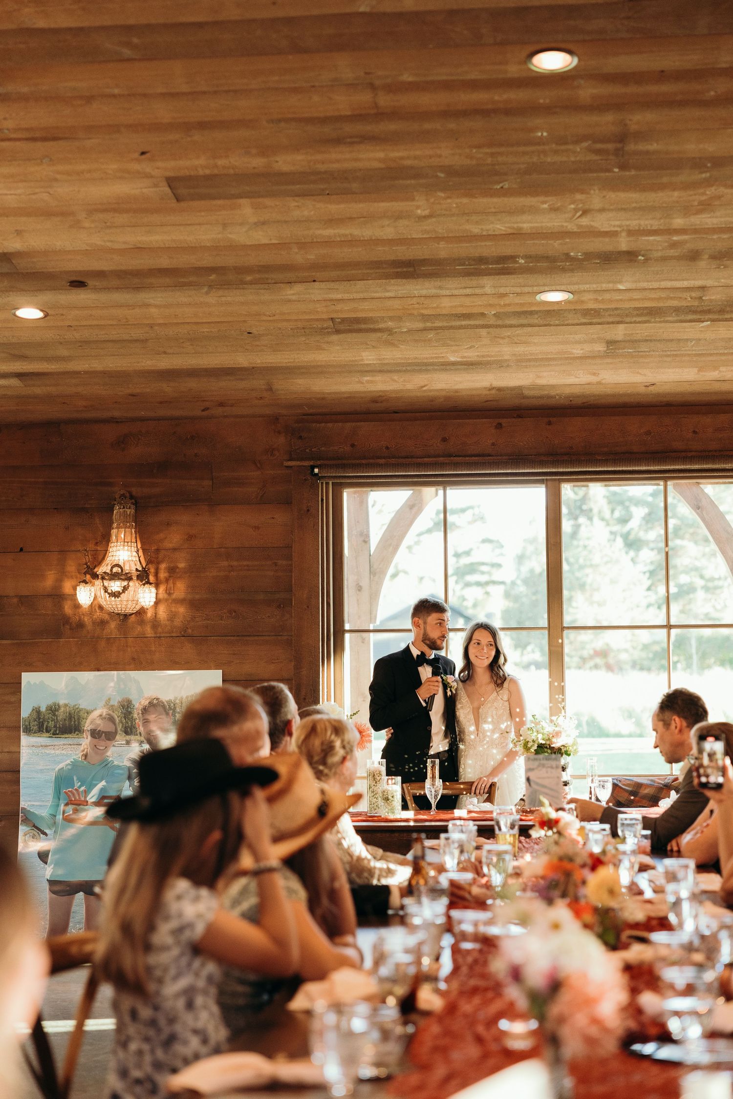 Interior of rustic wooden reception venue with warm lighting and table settings.