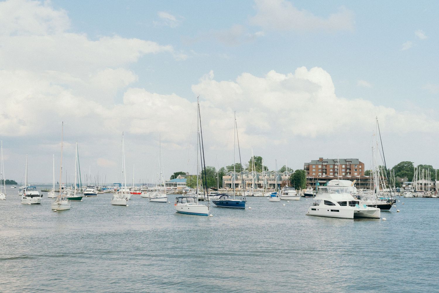 Panoramic view of boats and yachts anchored in a harbor on a sunny day.