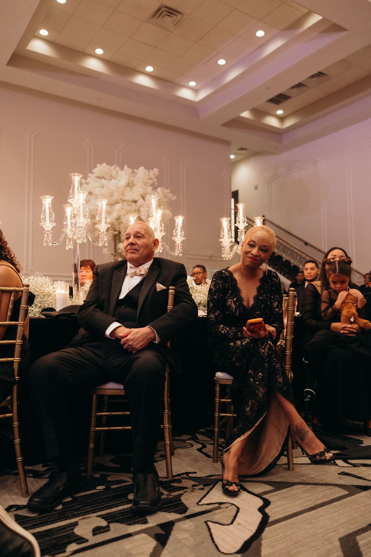 Wedding guests seated at reception tables with elegant candelabras and floral arrangements.