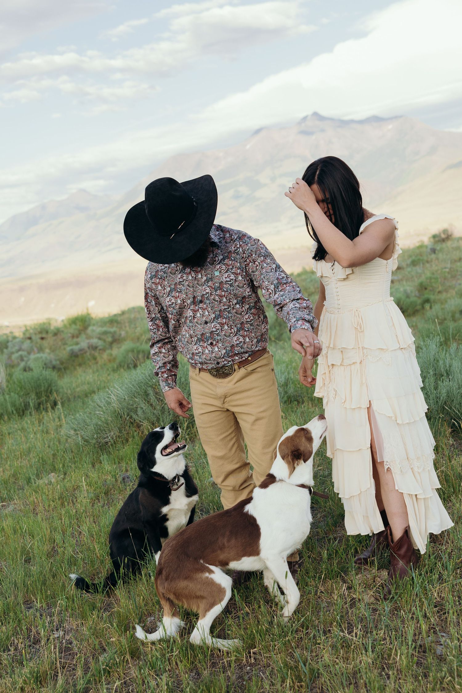 A couple and their border collie share a tender moment on a mountainside meadow.