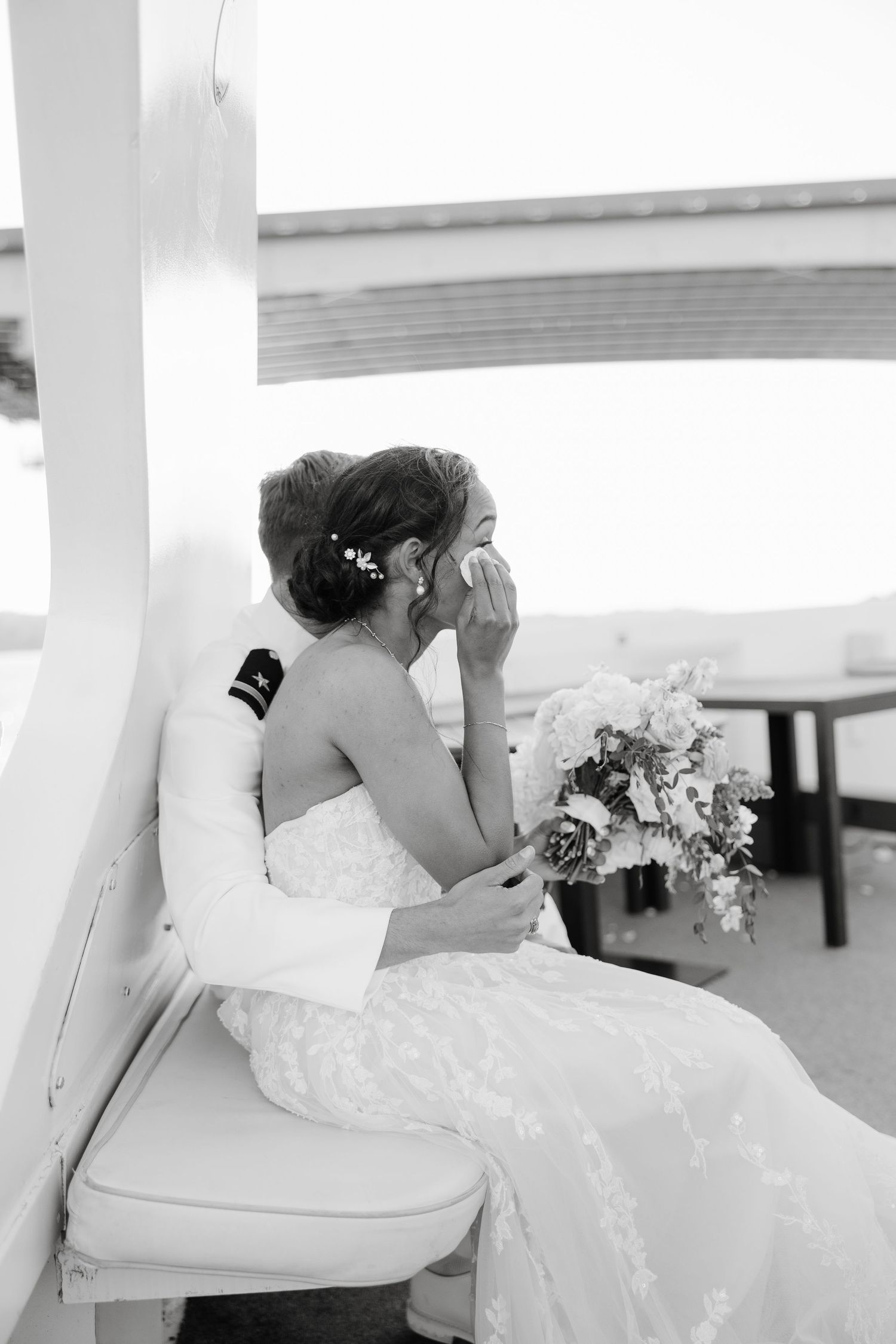 Elegant wedding couple poses together on white furniture during their celebration.