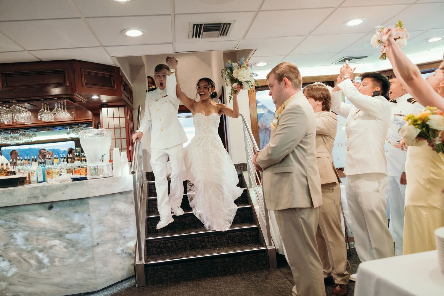 Wedding reception celebration with guests dancing and raising hands in a festive atmosphere.