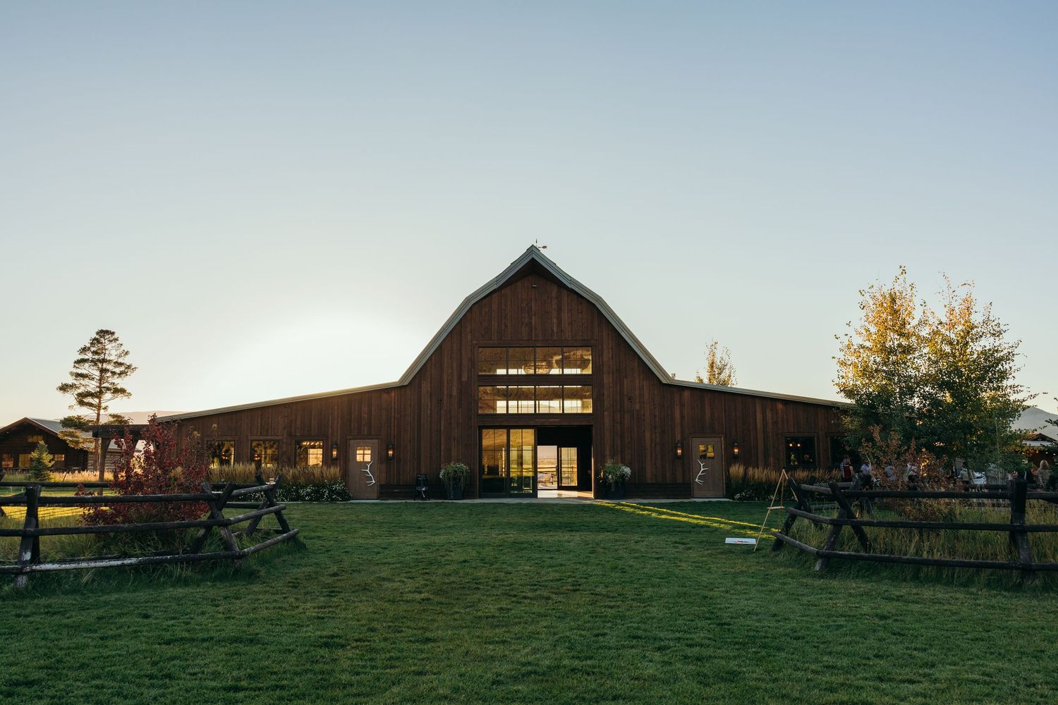 Panoramic view of a rustic barn venue nestled in rolling hills at sunset.