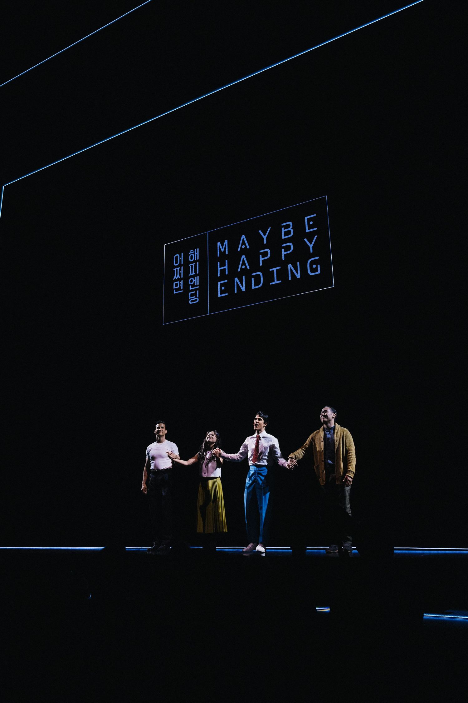 Dark stage with illuminated text reading 'MAYBE HAPPY ENDING' visible in blue lighting.