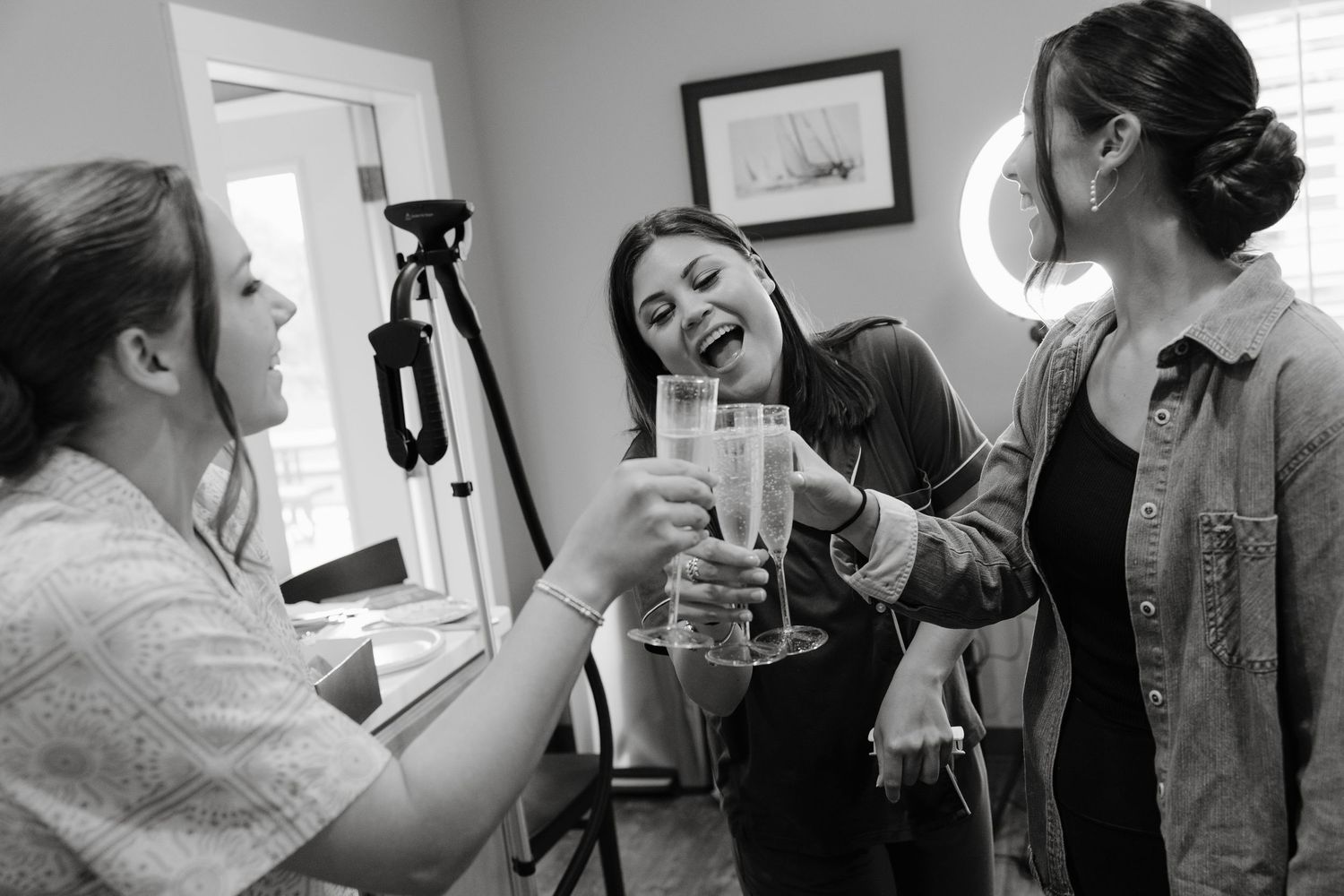 Black and white photo of people laughing and enjoying drinks together.