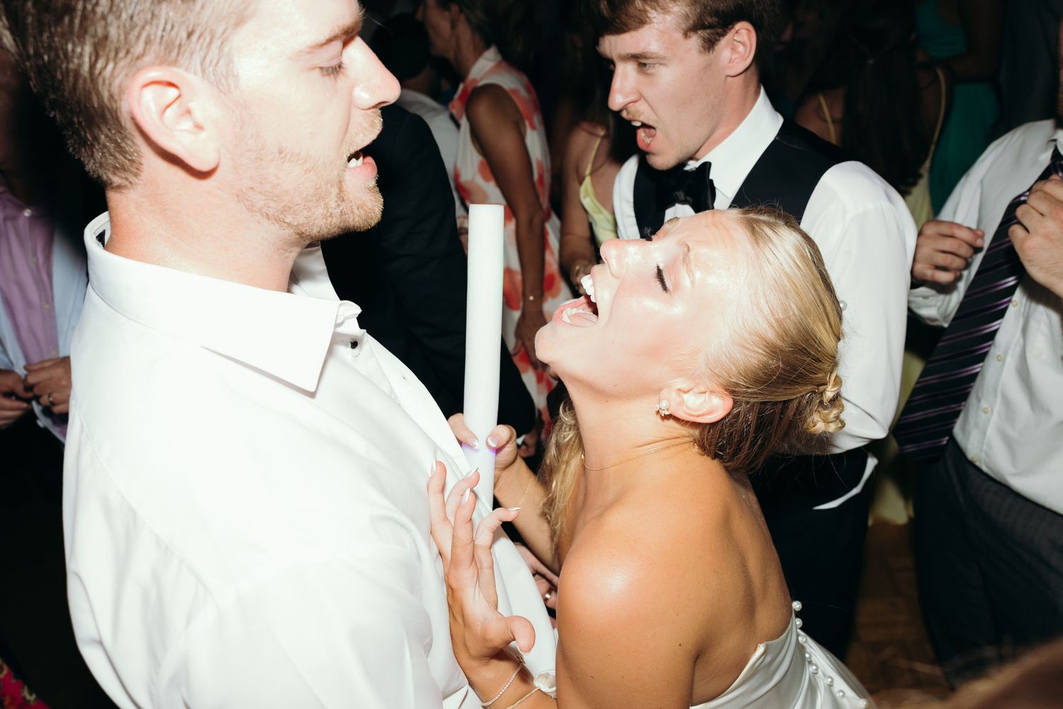 Guests dancing and enjoying themselves at a dimly lit wedding reception.