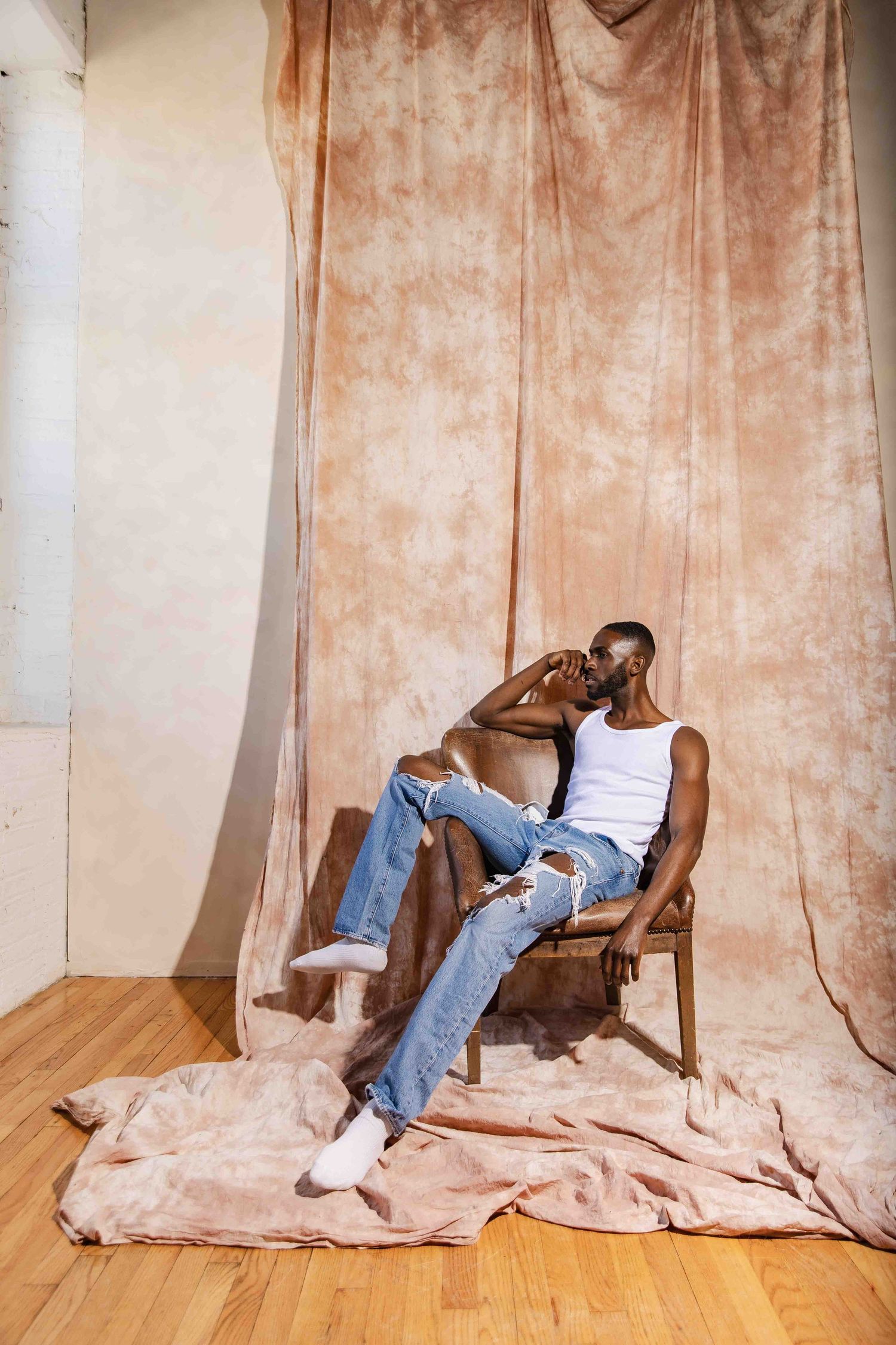 Four sequential photos show a person in jeans falling behind a beige curtain on a wooden floor.