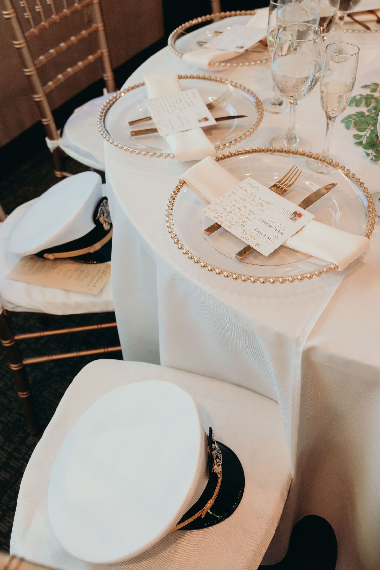 Elegant table settings with white linens and gold charger plates at a formal reception.